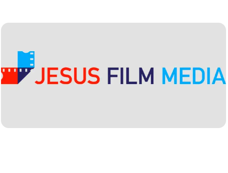 Açyk çal fonuň üstünde gyzyl, gök we gara reňkli kino klapperboard (çapraz) nyşany we onuň yzyndan gyzyl, gara hem-de gök reňklerde ýazylan “JESUS FILM MEDIA” sözleri bolan logo.