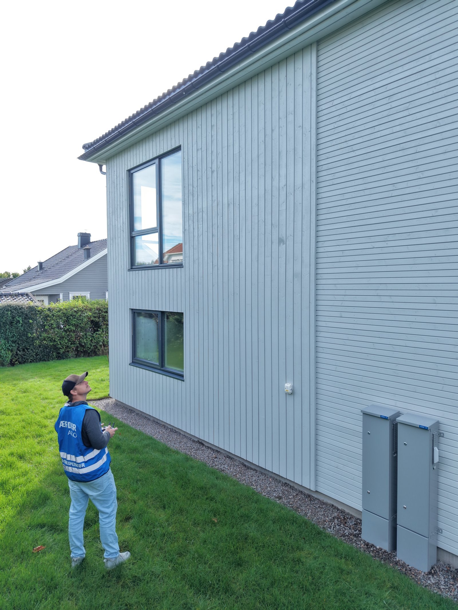 Droneoperatør fra Færder Aero i arbeid ved en husfasade, med blikket rettet mot dronen