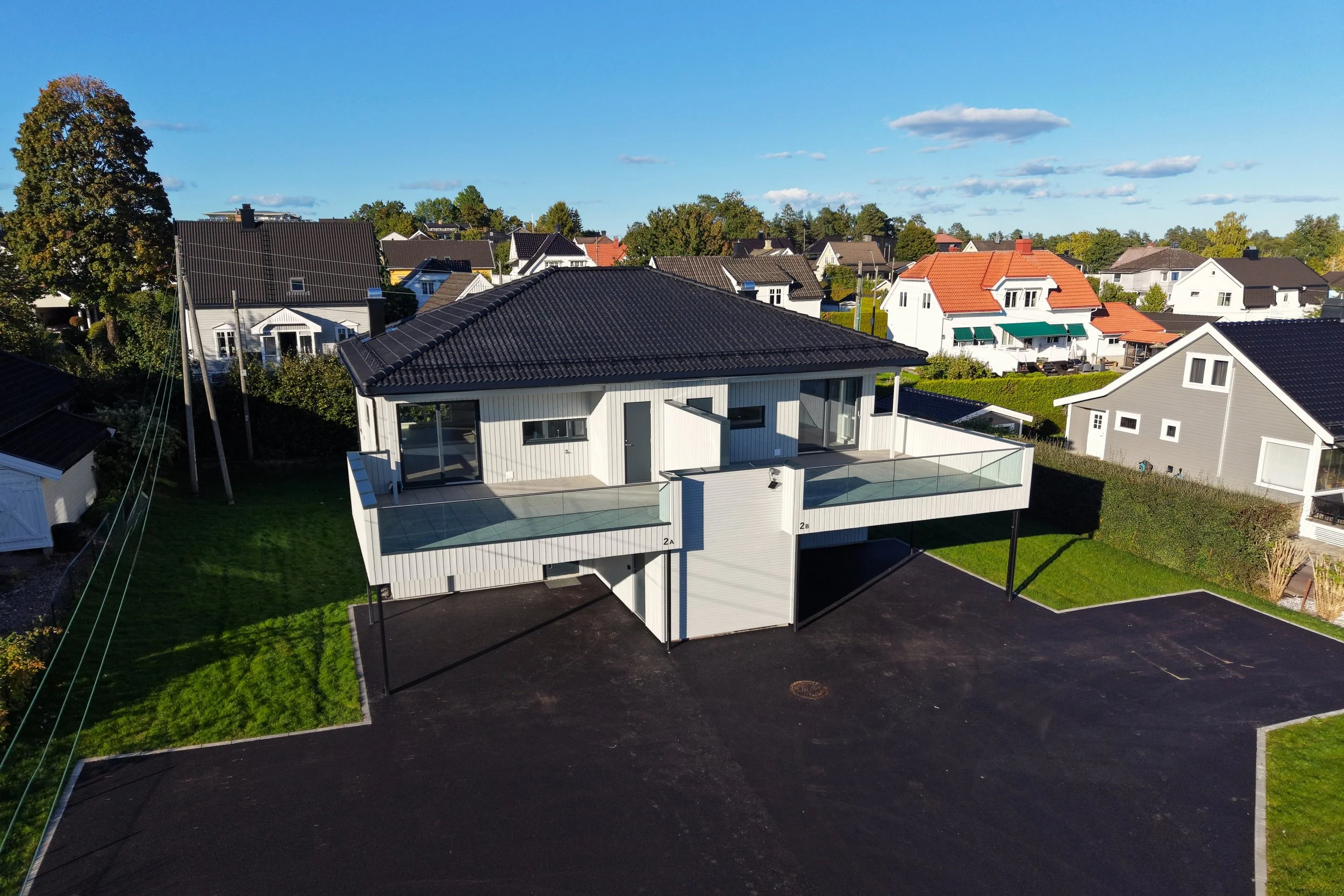Dronebilde av ferdig enebolig med svart tak og terrasse