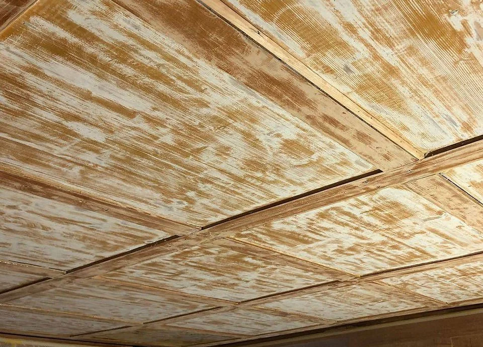 Decke mit abblätternder, alternder weißer Farbe in einem Raum.