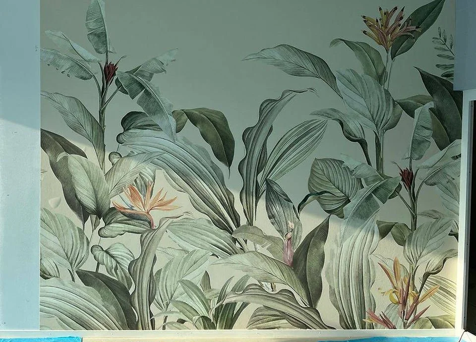 Wand mit Tapete von großen grünen Blättern und Blumenmuster