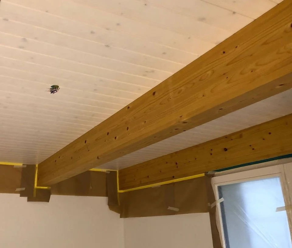 Holzbalken an Zimmerdecke mit Dämmmaterial und Verkabelung