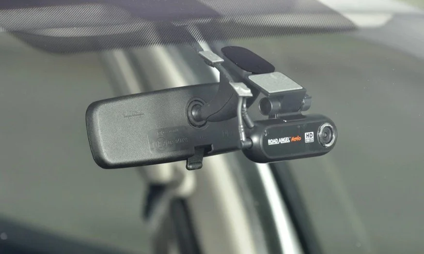 A car's interior rearview mirror with an attached dashboard camera.