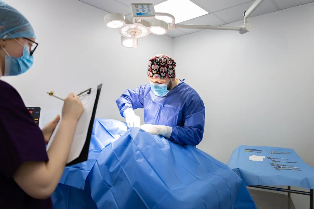 Surgeon performing a procedure in an operating room with a nurse taking notes.