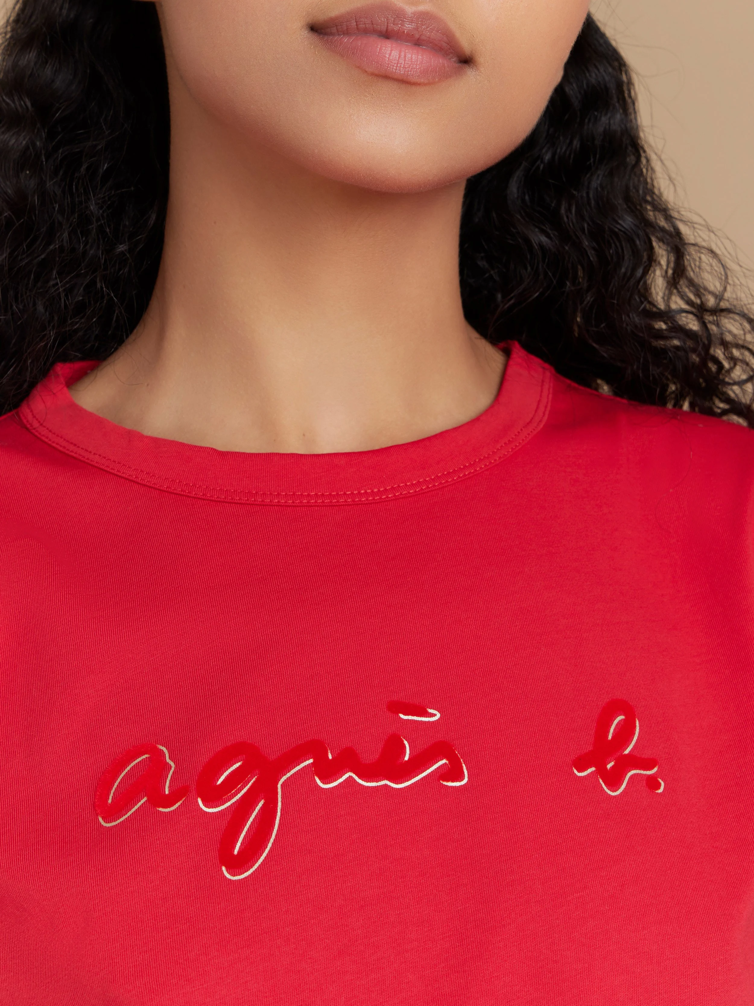 Cercle rouge et écriture cursive rouge sur un haut rouge, portrait jusqu'aux épaules.