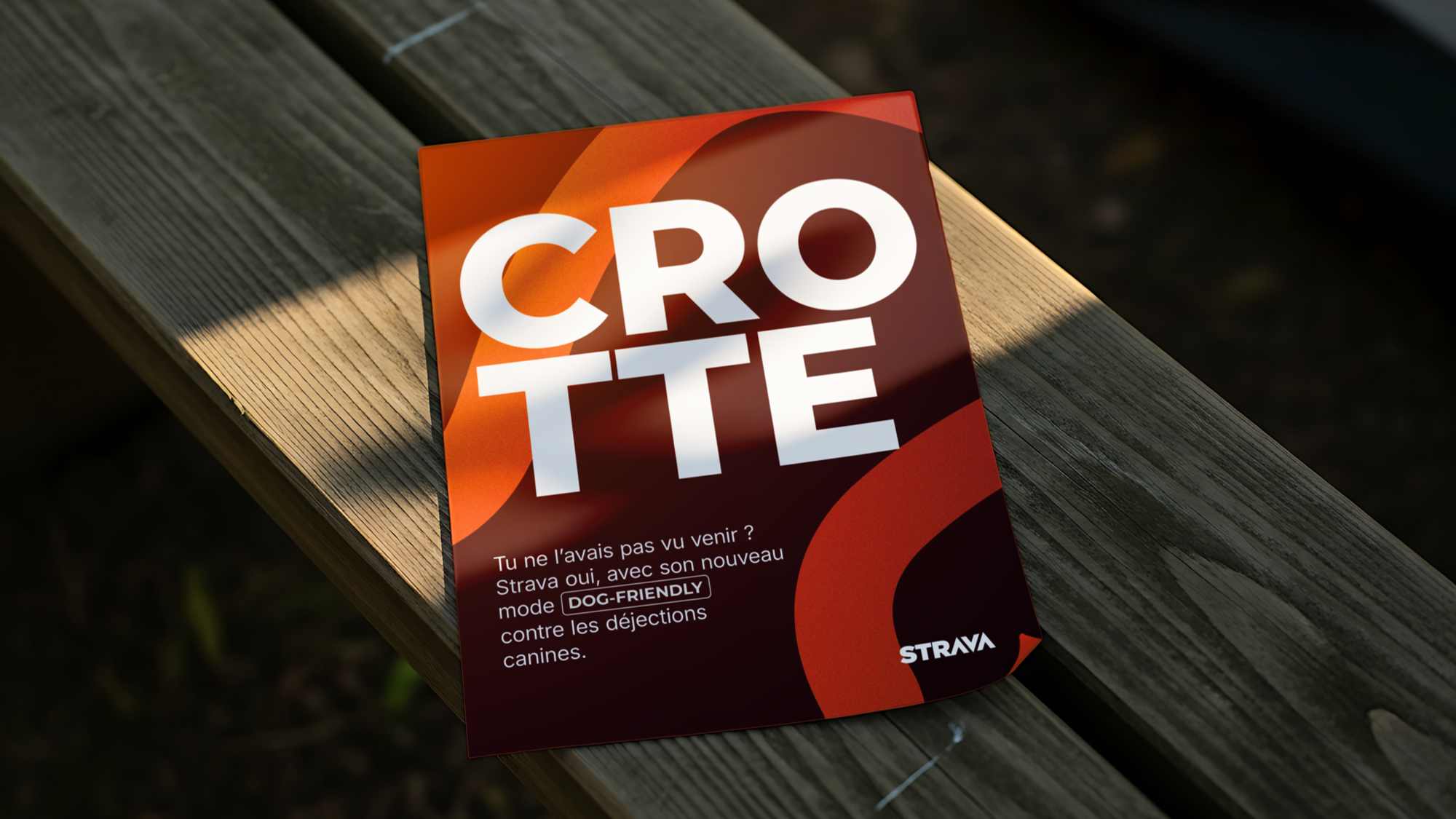 Une affiche publicitaire de Strava avec le mot 'CROTTÉ' en grosses lettres blanches sur un fond coloré orange et rouge, évoquant un mode de course à pied 'DOG-FRIENDLY' contre les déjections canines.