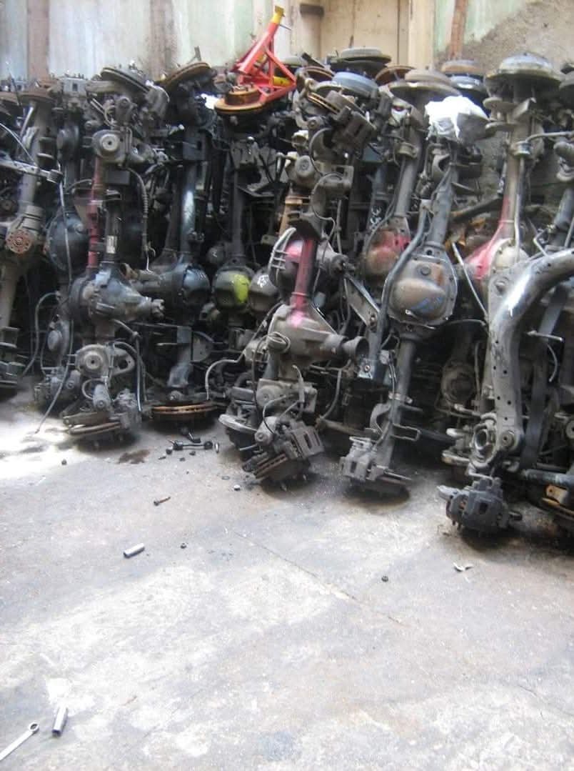 A large pile of used car engine parts and transmissions stored outdoors.