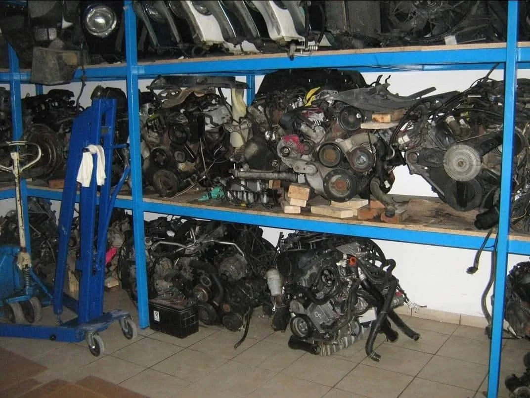 Various car engines and parts stored on metal shelves in a workshop or garage.