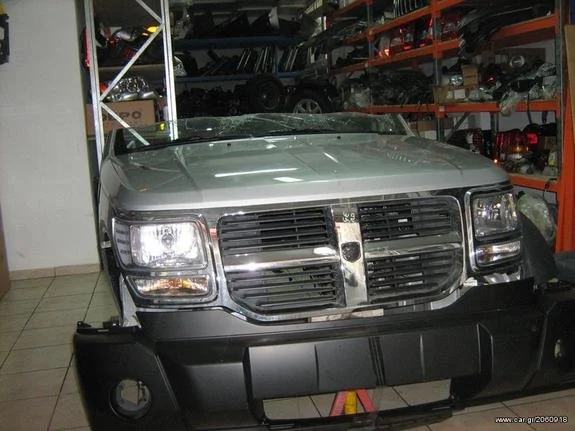 Silver SUV inside a warehouse workshop with car parts on racks in the background.