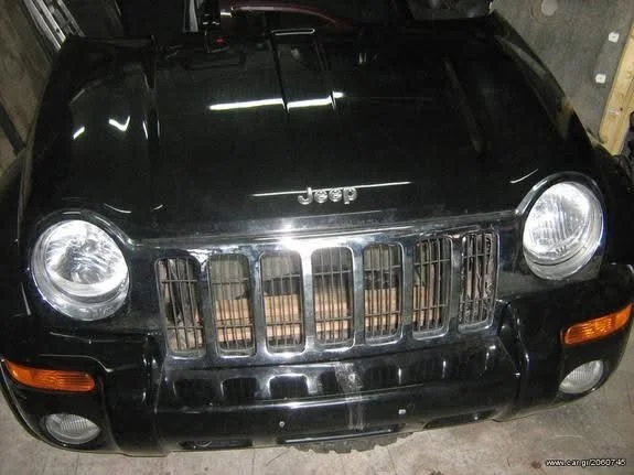 Front view of a black Jeep SUV in a garage, showing the grille, headlights, and Jeep emblem on the hood.