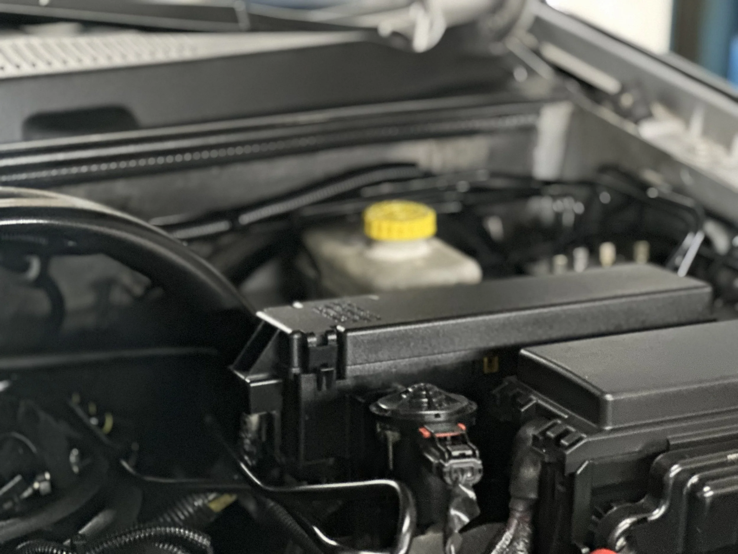 Close-up of a car engine with a yellow cap and various black components.