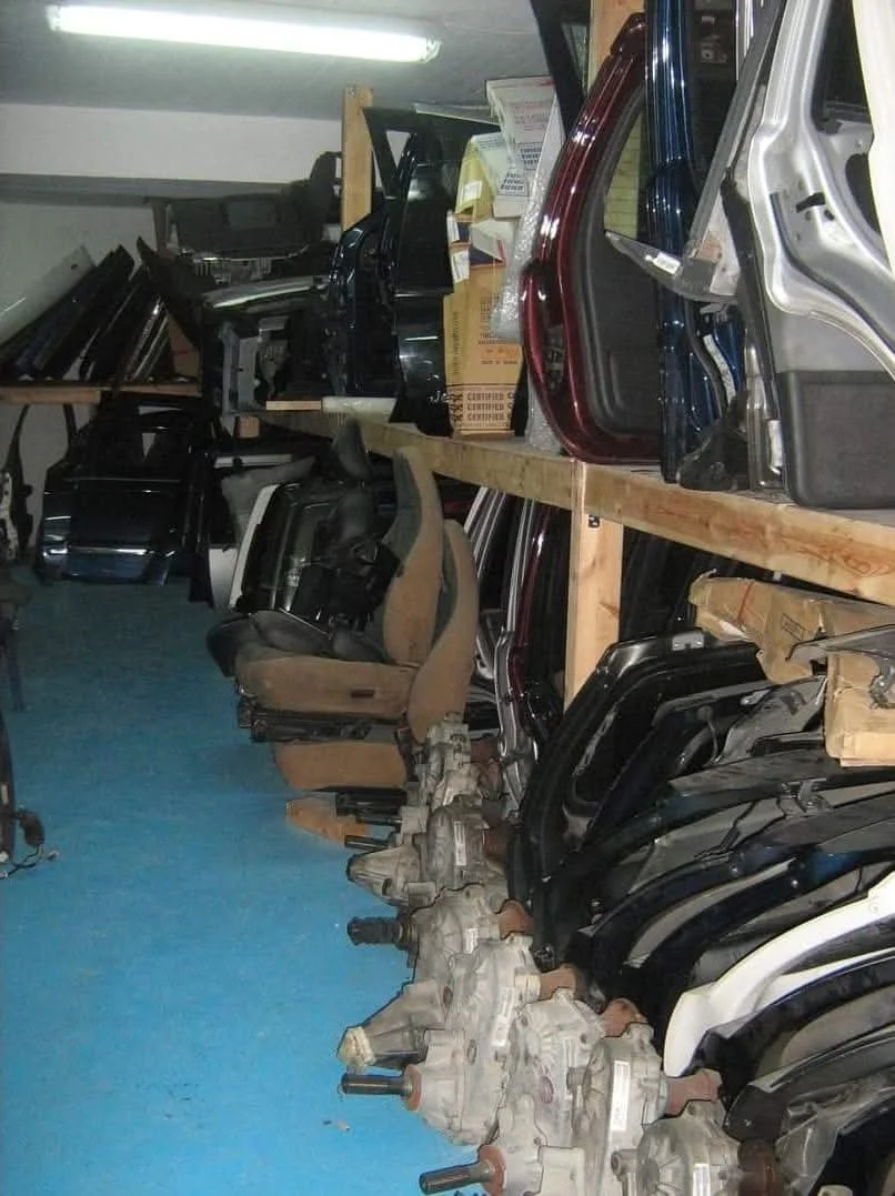Shelves filled with car parts and truck seats stored in a workshop or warehouse.