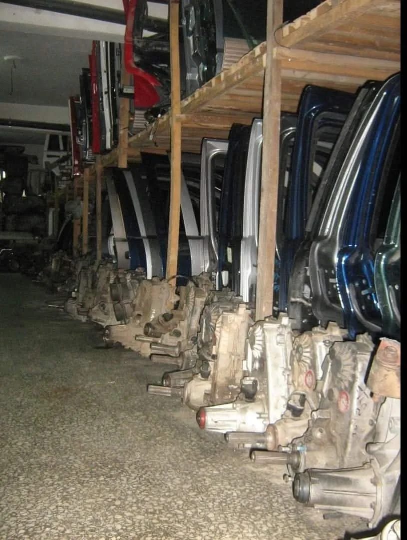 Rows of automotive parts, including vehicle doors and transmissions, stored on shelves in a warehouse.