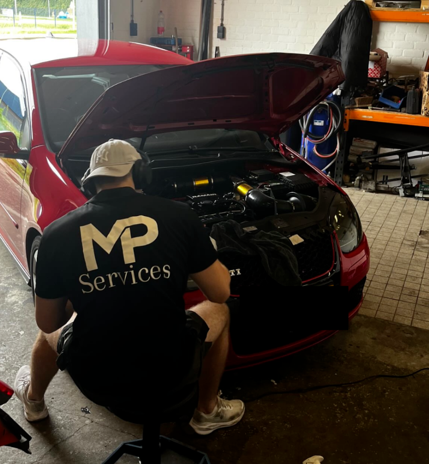 Mankracht in een garage die aan een sportwagen werkt met de motorkap omhoog.