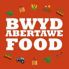 Text reading 'BWYD ABERTAWE FOOD' with icons of vegetables, gifts, a tractor, and food items on a red background.