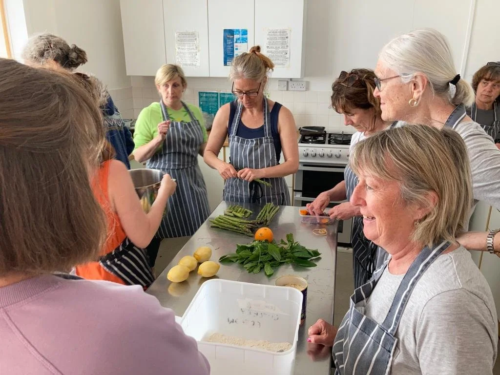 Group of women in aprons preparing vegetables in a kitchen