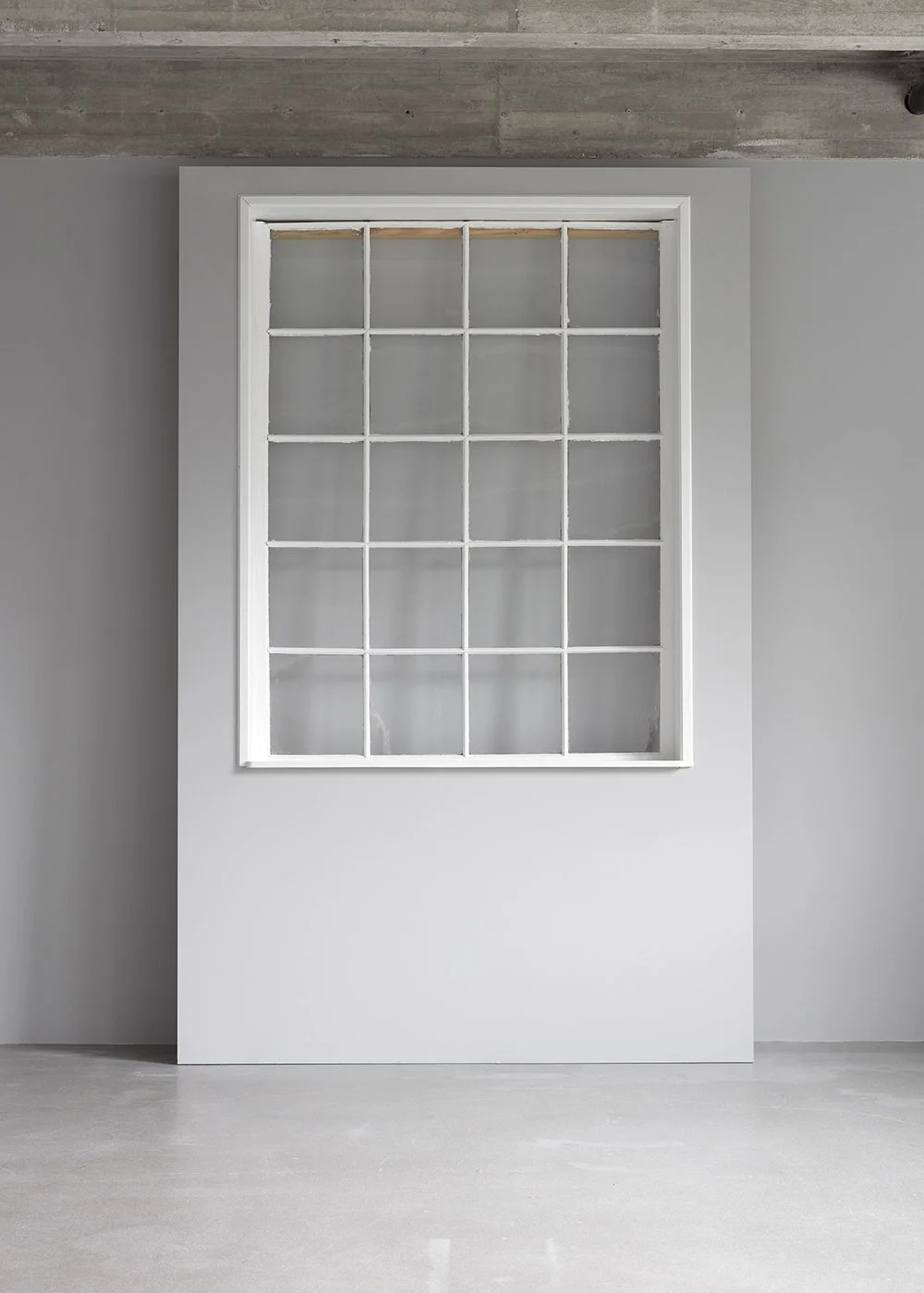 Empty room with a large white window and gray walls.