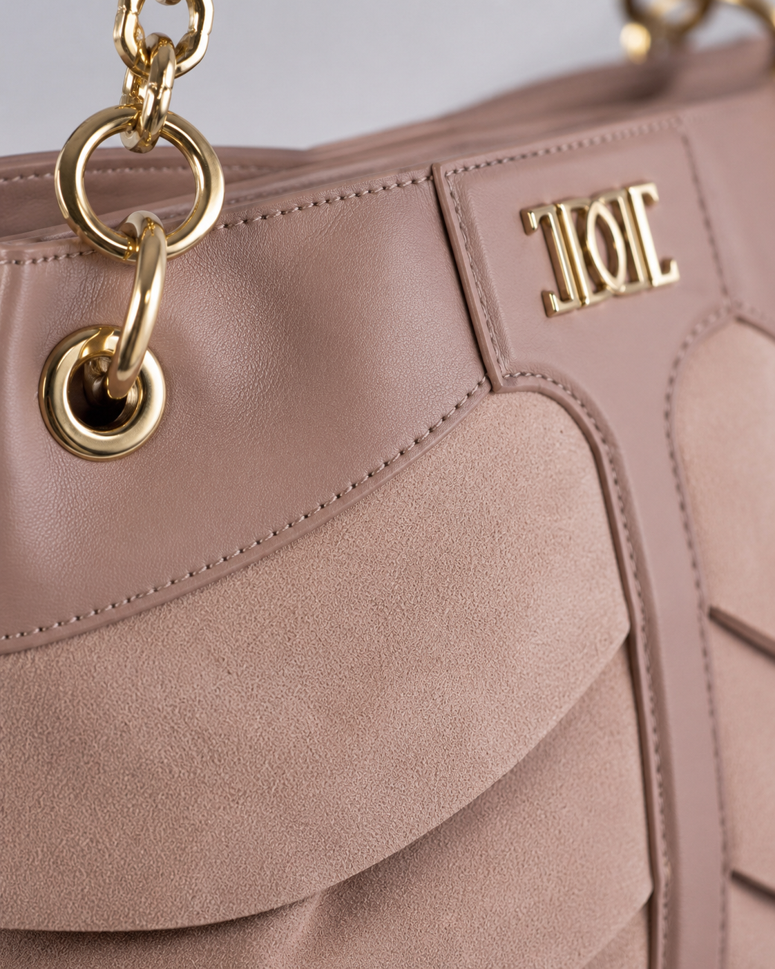 Close-up of a pink designer handbag with gold hardware and a brand logo that reads 'TODI' in gold letters.