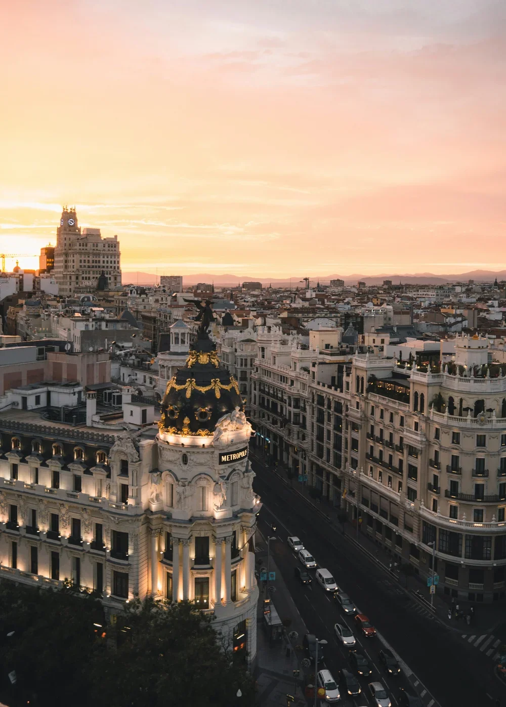 A view of Madrid at sunset, showing historic buildings and streets with traffic.
