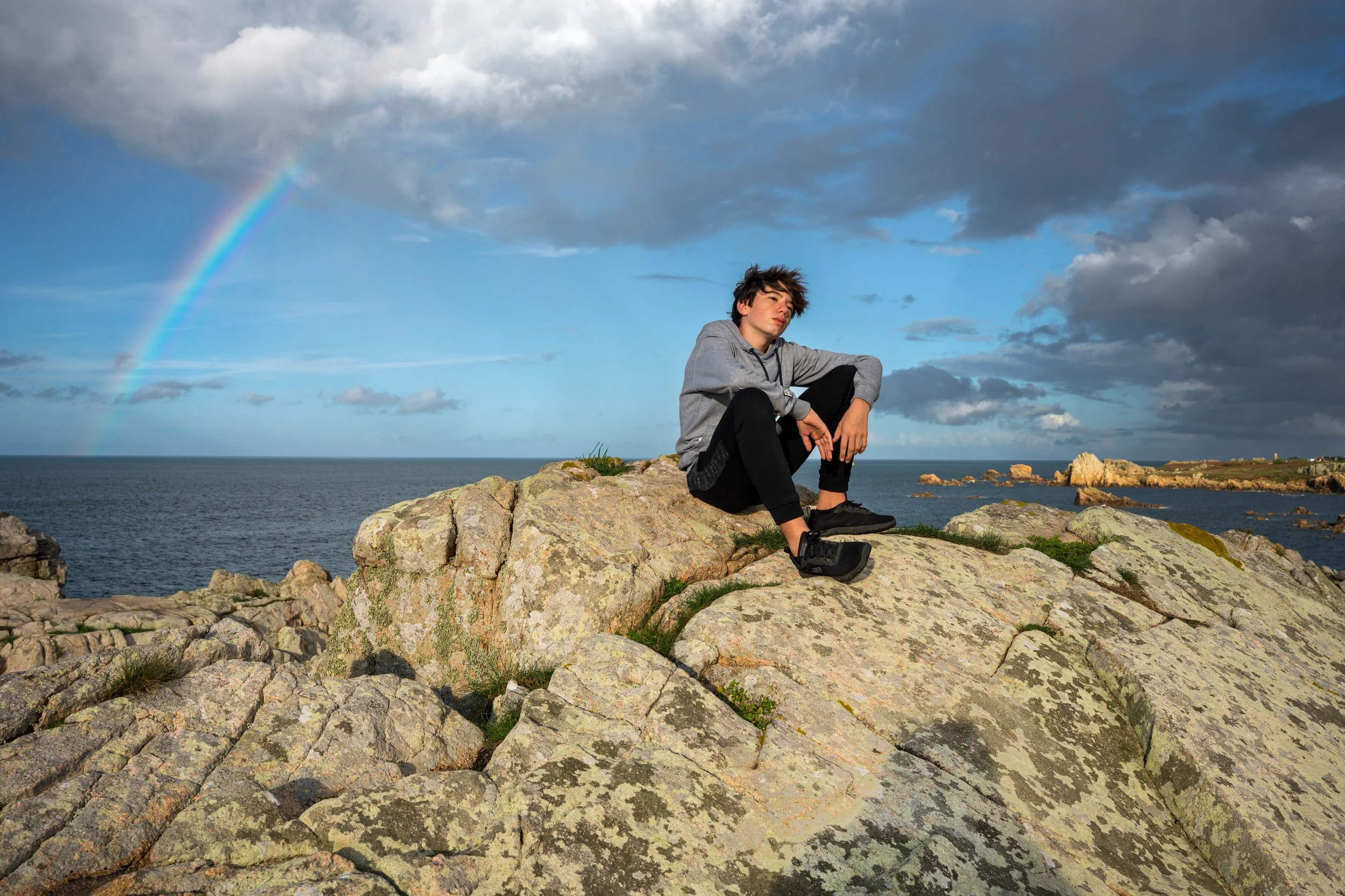 Jeune homme devant la mer sous un arc en ciel