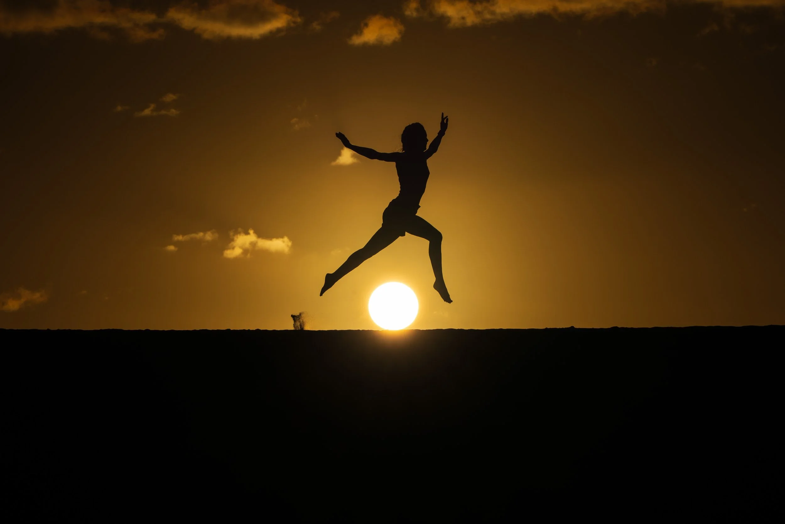Femme qui saute au dessus du soleil, ombre chinoise au soleil couchant