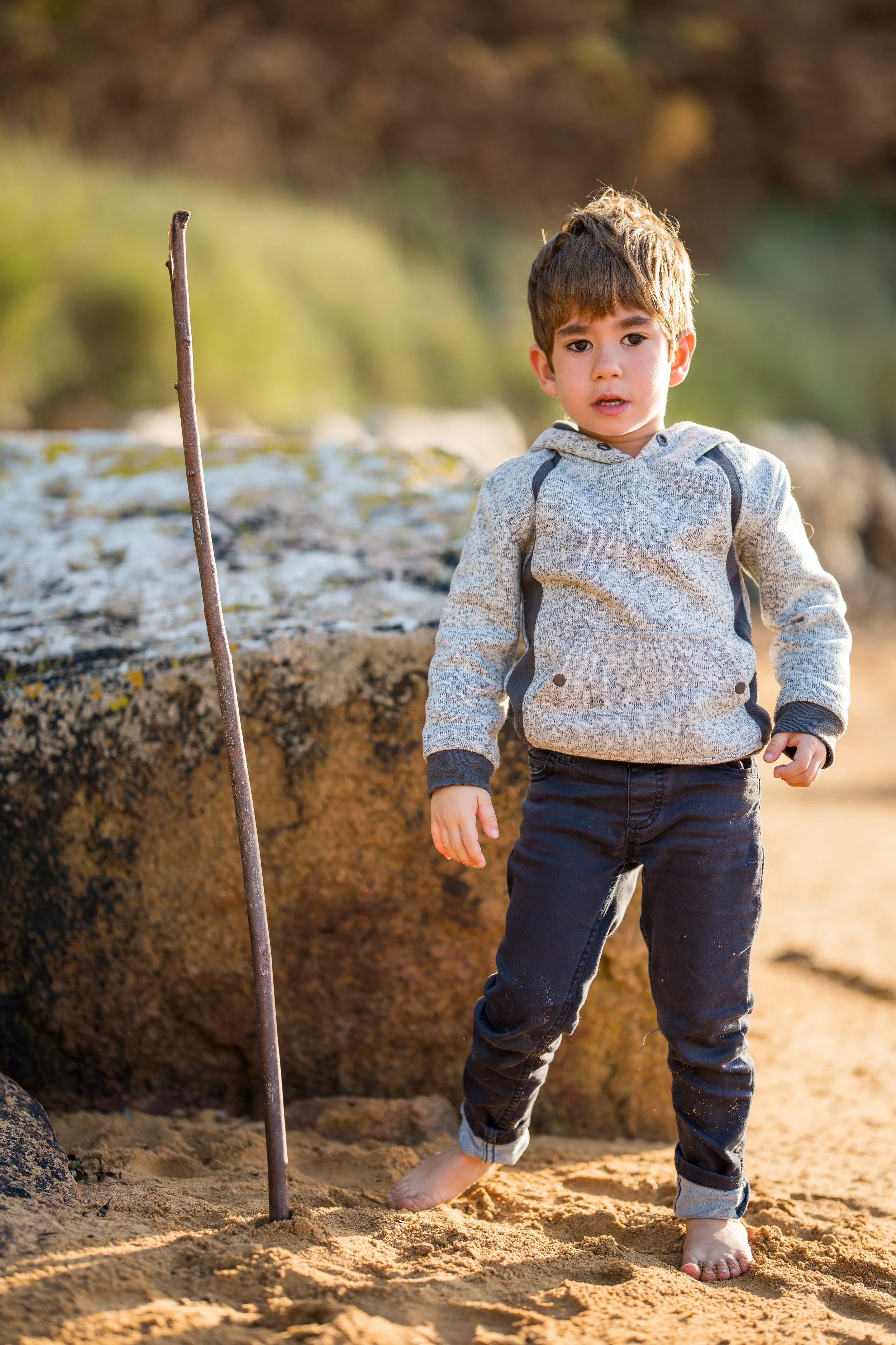 Enfant dans le sable jouant avec un bâton 