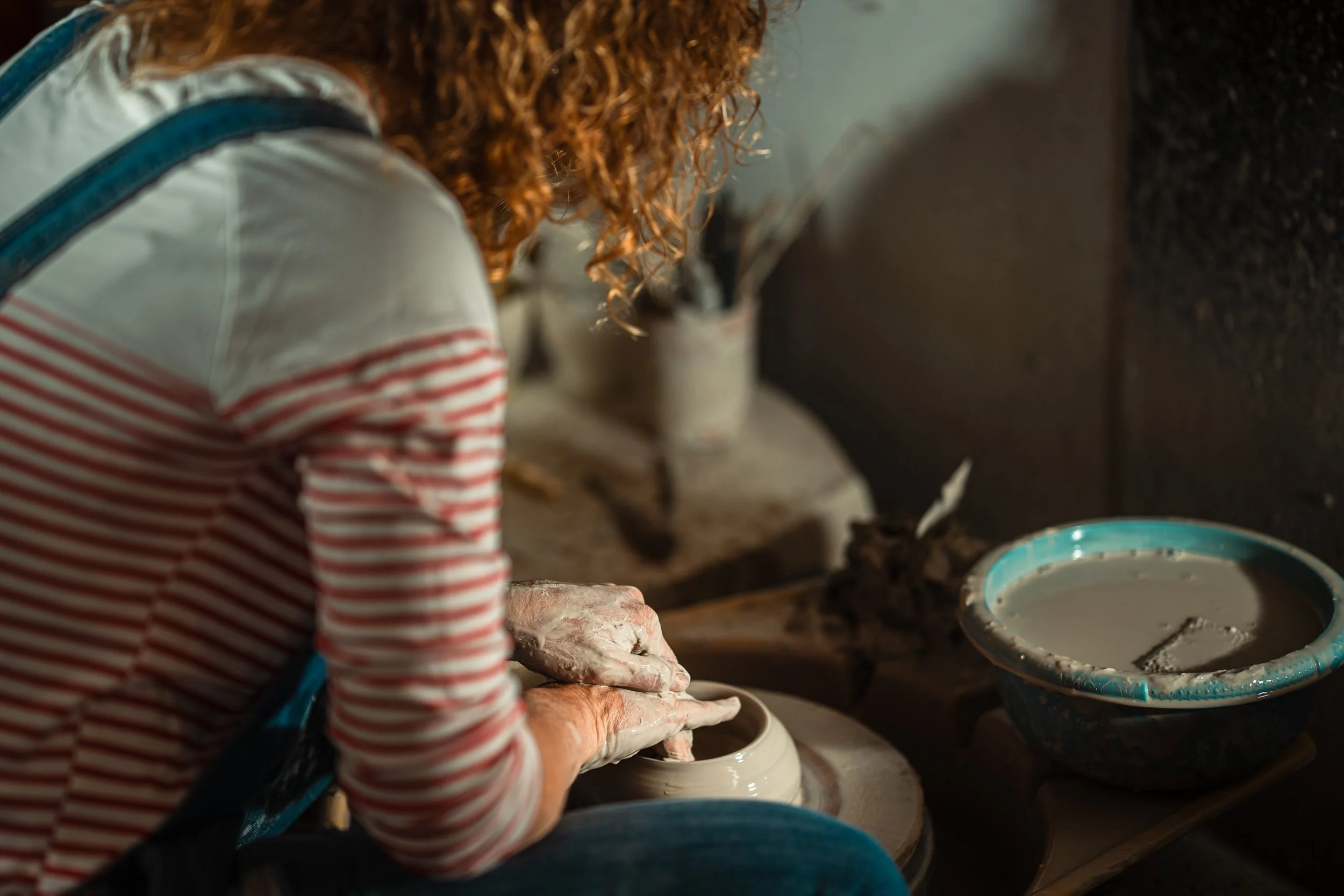 Artisan céramiste en train de tourner dans son atelier, détail des mains