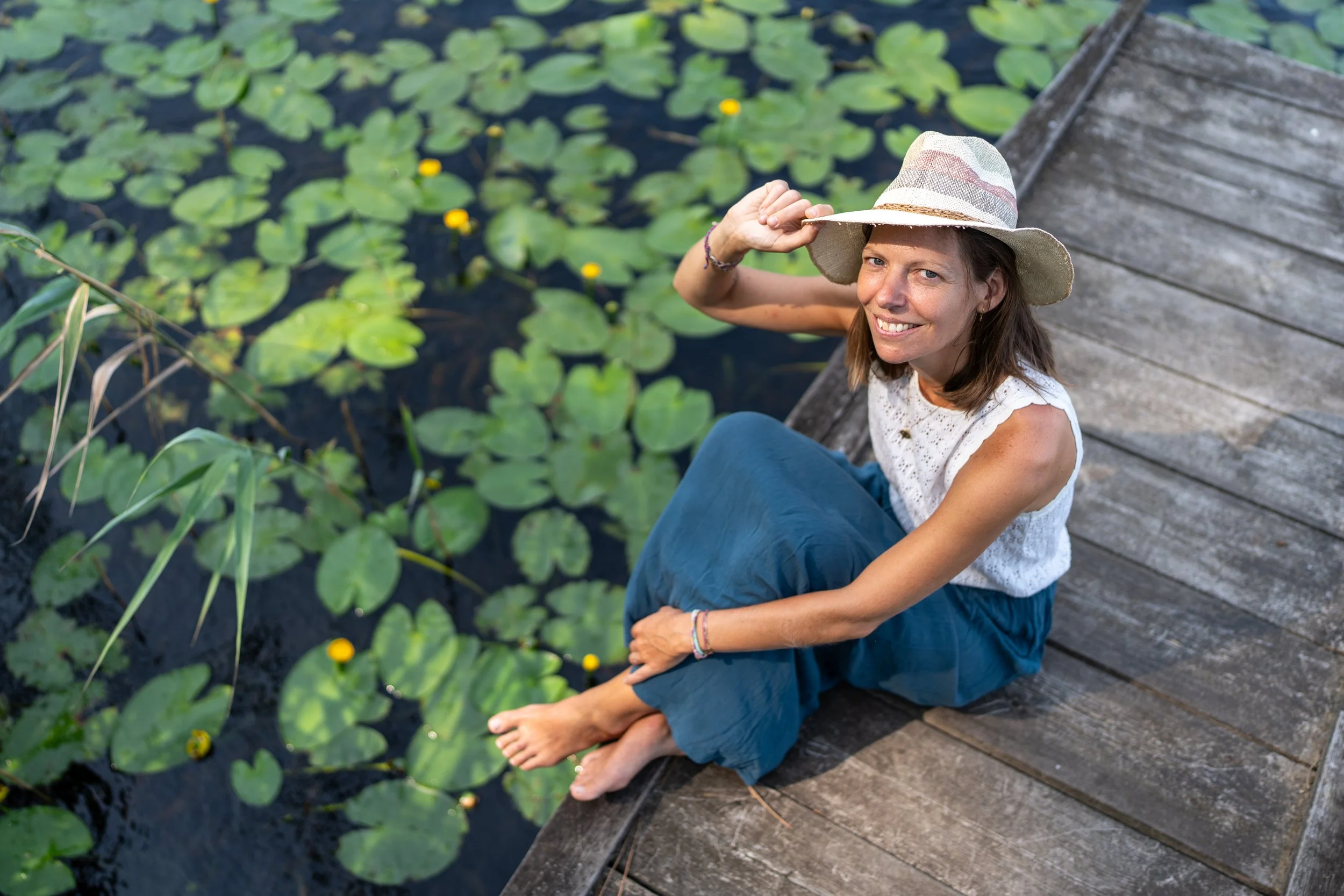 Femme sur un ponton de bois au milieu des nénuphars