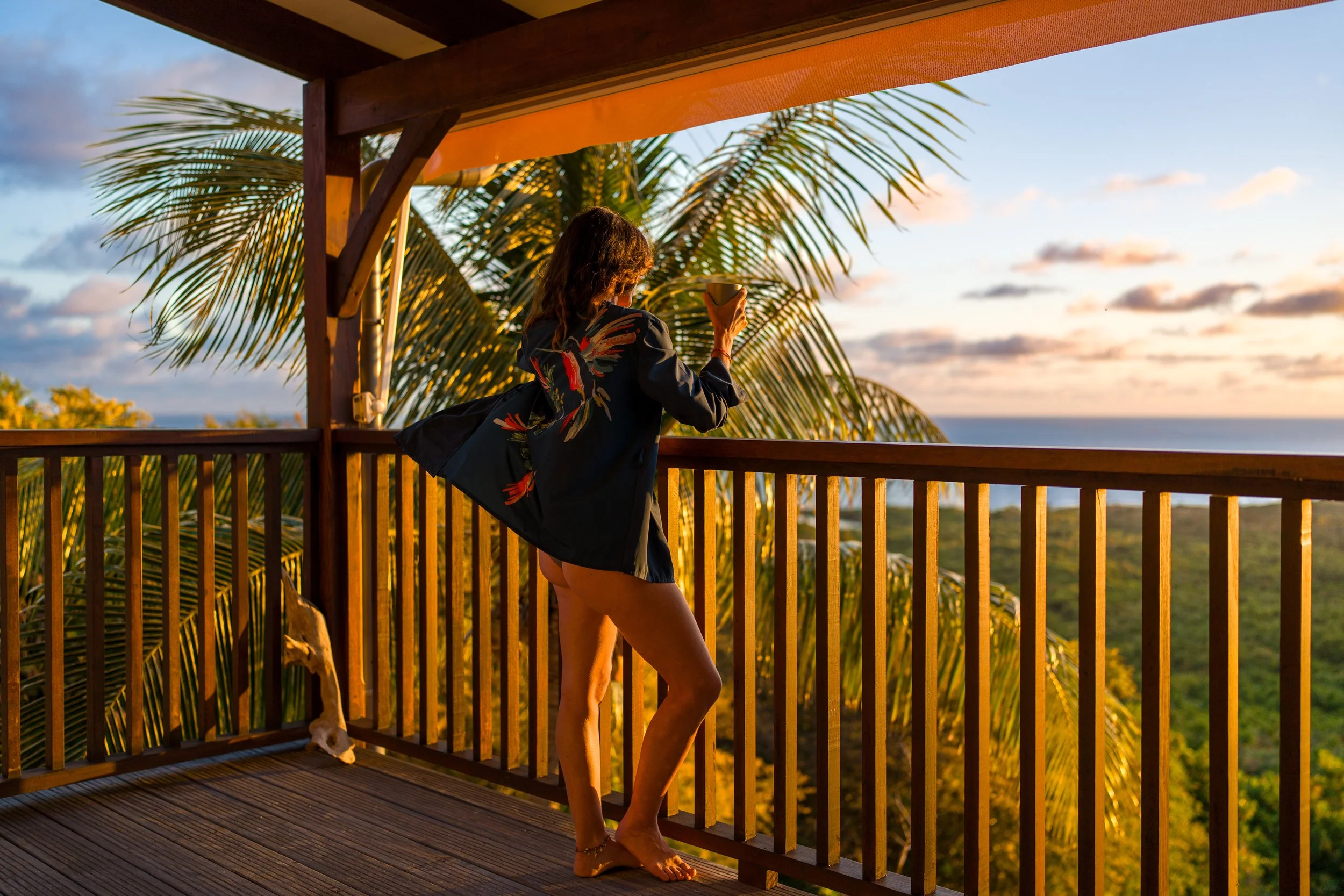 Femme sur sa terrasse au soleil levant sous les tropiques