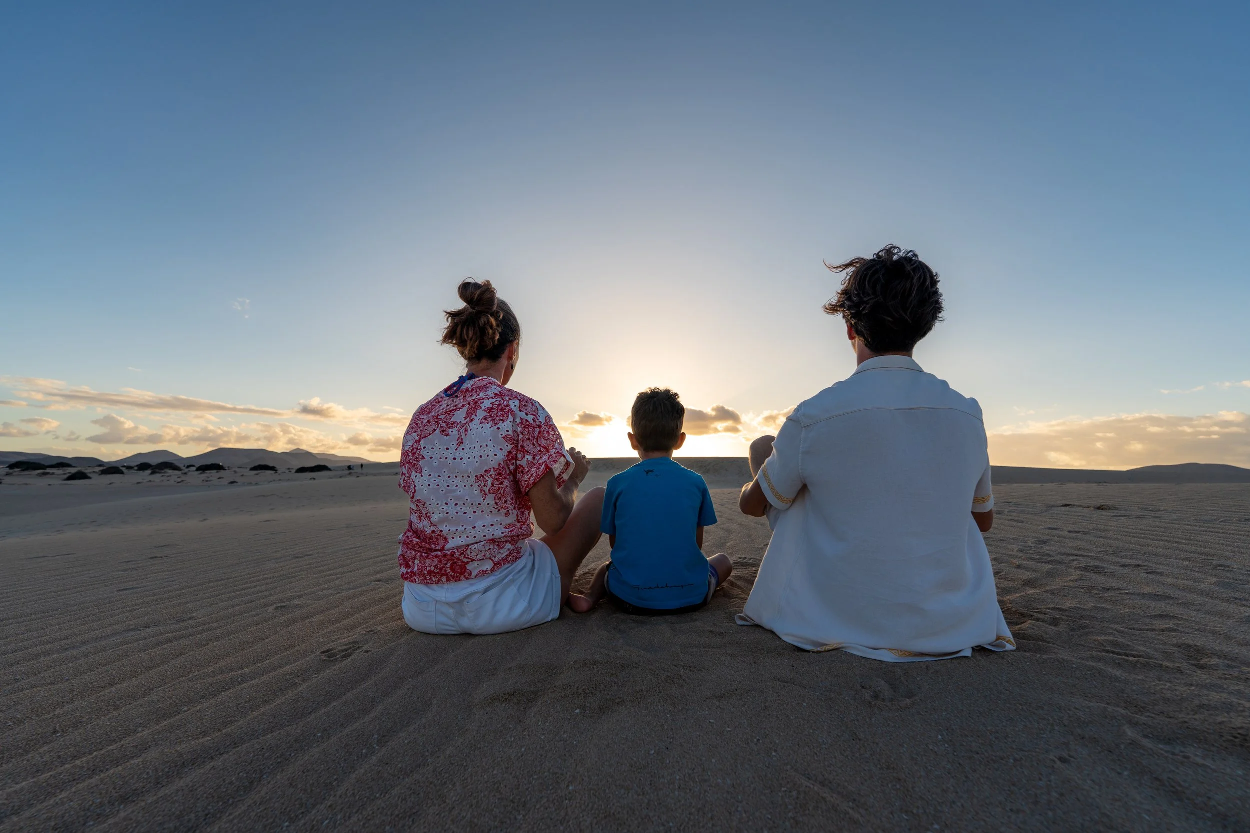 Famille regardant le soleil couchant dans les dunes