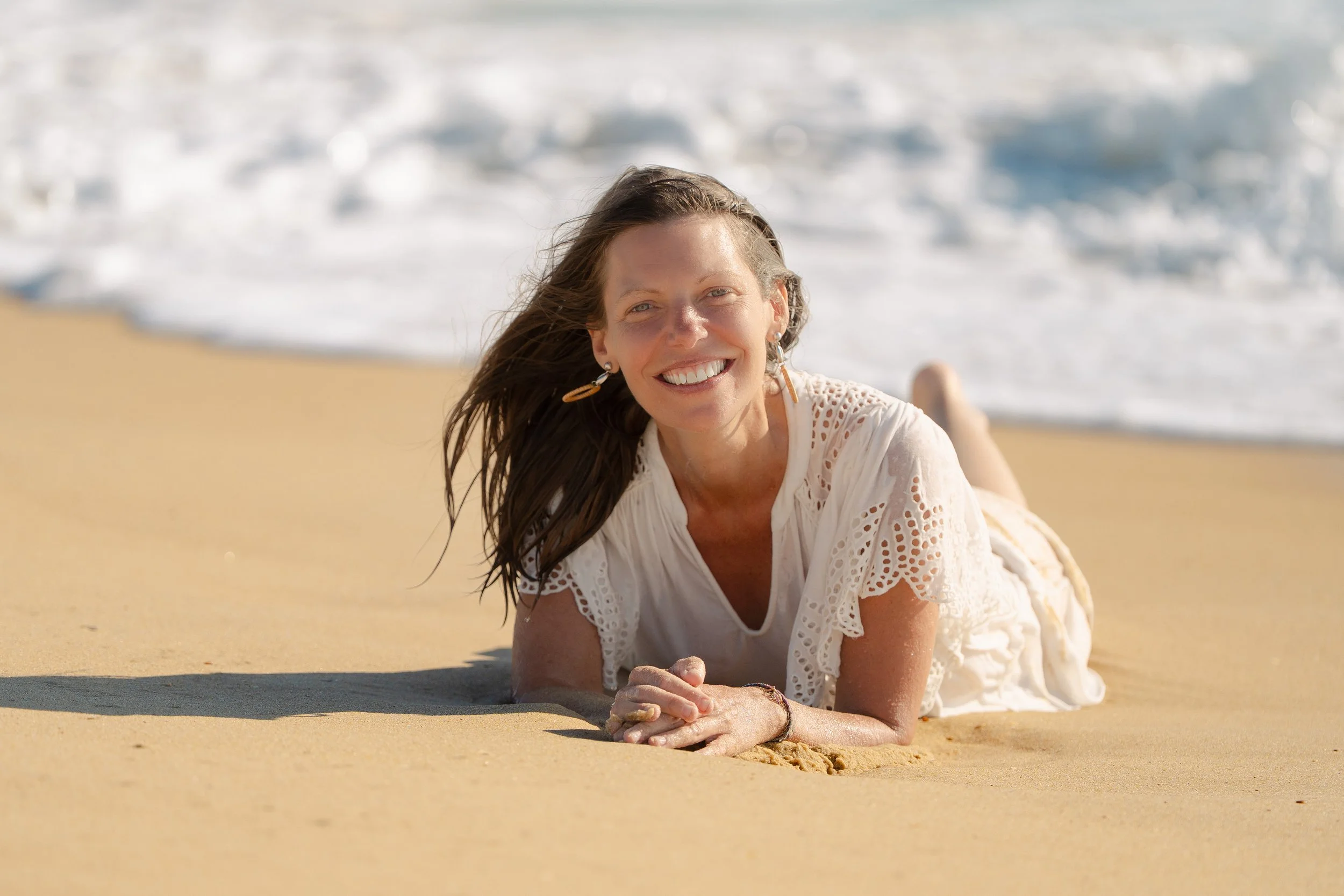 Femme souriante allongée sur la plage dans les vagues