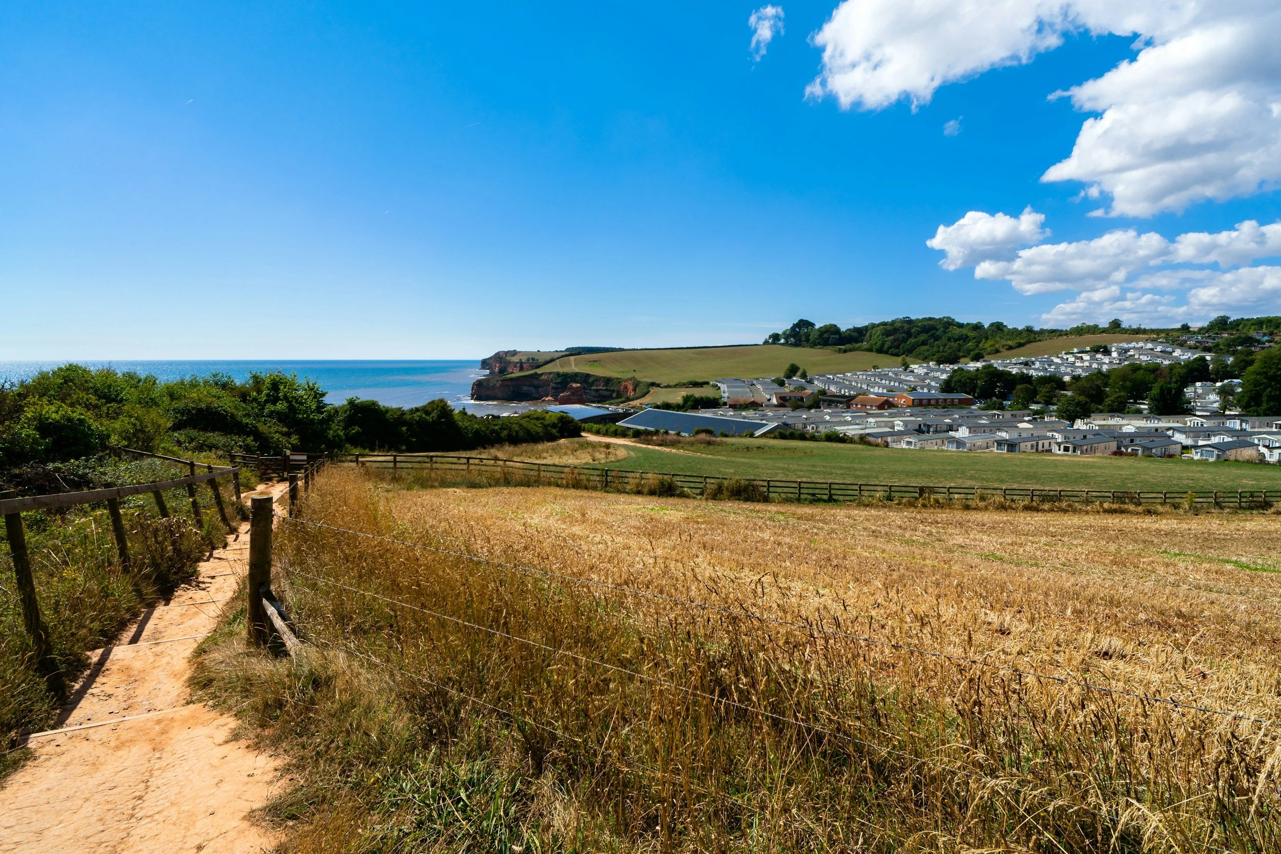 A grass area with a view of the sea and a caravan park in the distance. Overhead is a clear blue sky. What could possibly go wrong?