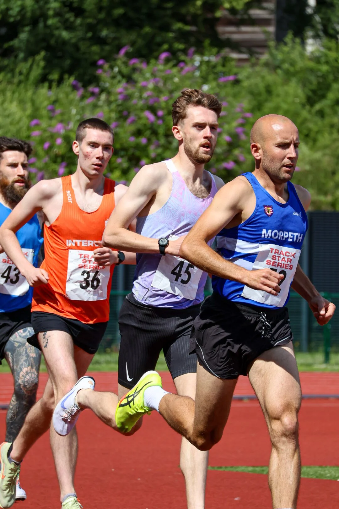 Male athletes running on a track during a race.