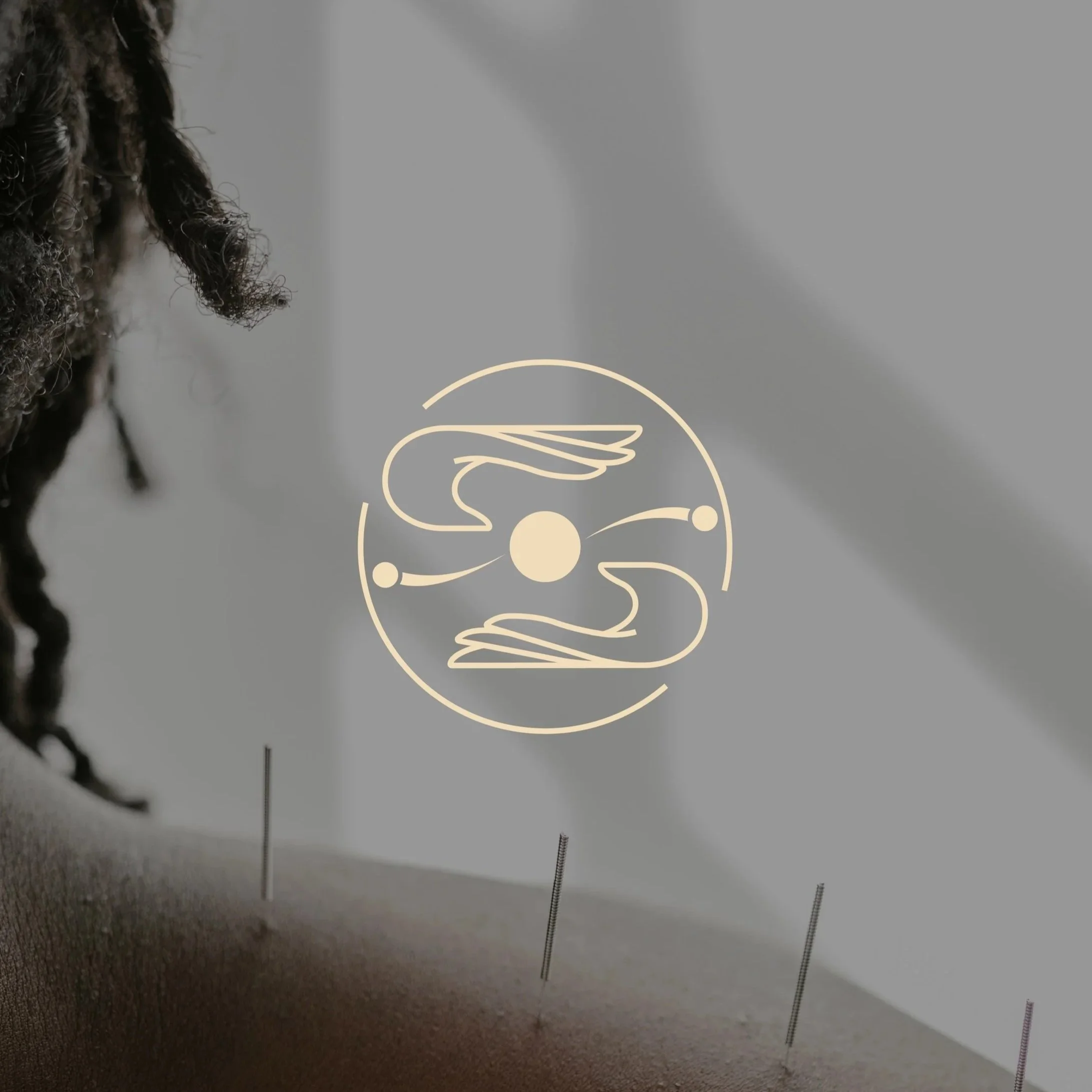 Une personne vue de dos, avec des cheveux bouclés. Sur la vitre, un dessin minimaliste représentant deux mains se faisant face autour d'un cercle, avec deux petits points de chaque côté et une ligne courbe.