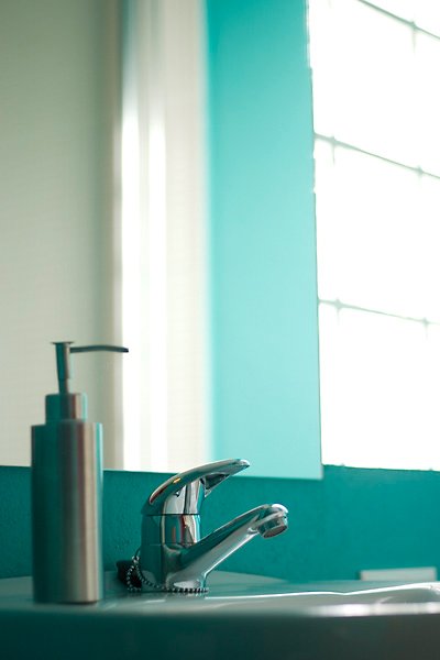 Lavabo con dispensador de jabón en un baño con ventana en hotel rural la peregrina