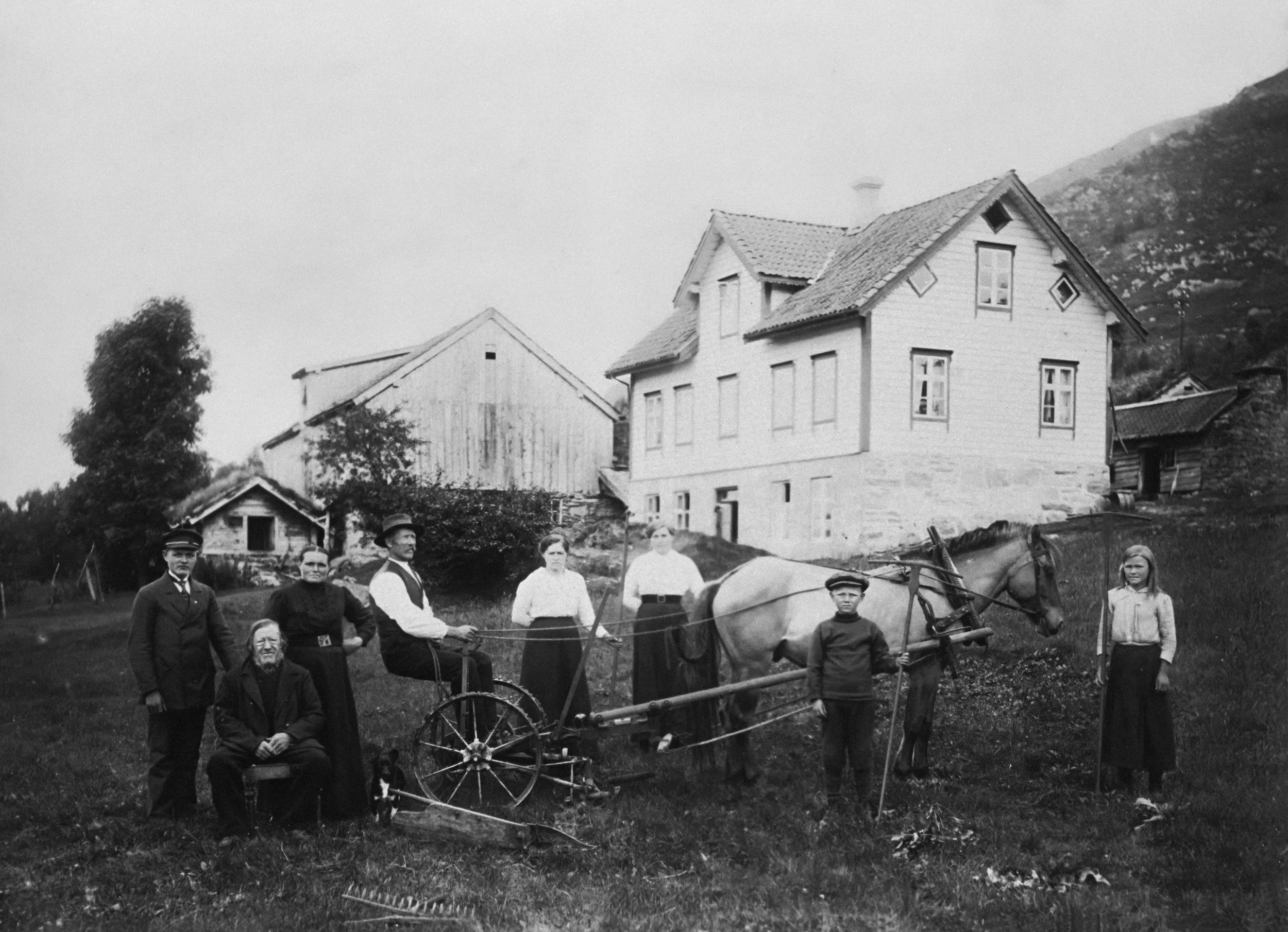 Vintage black and white photograph of a farming family with horse-drawn machinery