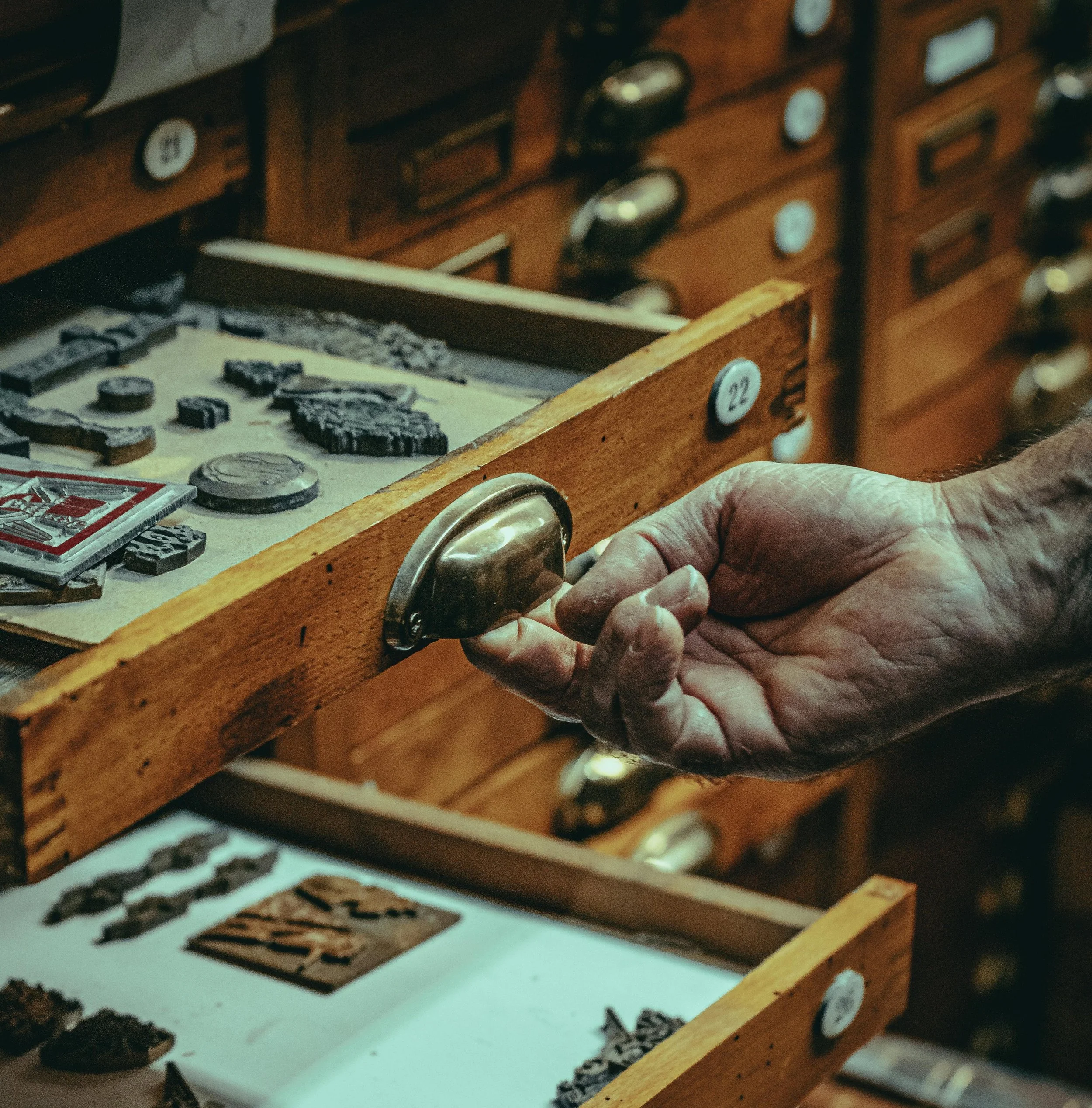 Hand opening a drawer containing historic artefacts