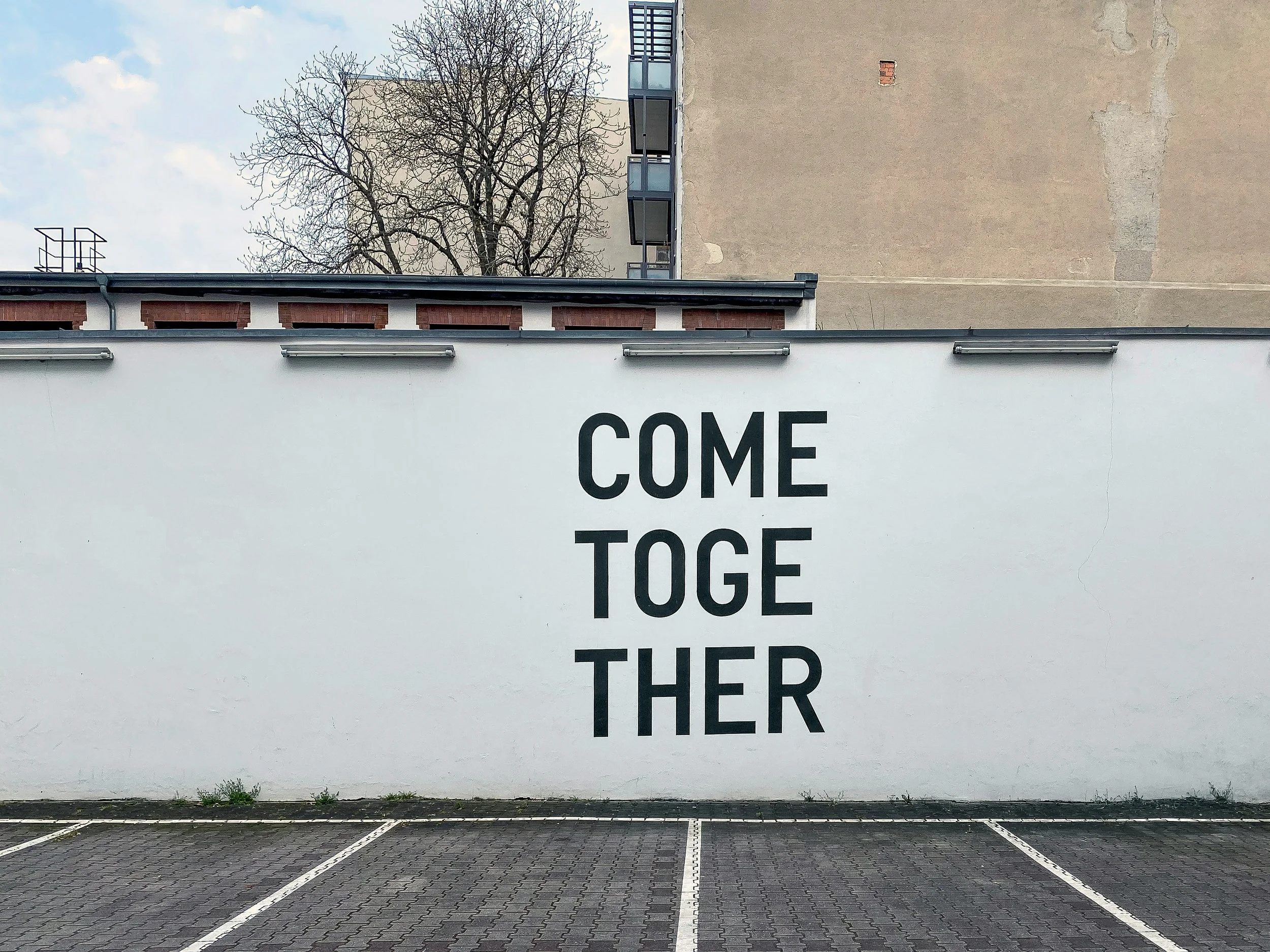 A large white wall with come together written on it