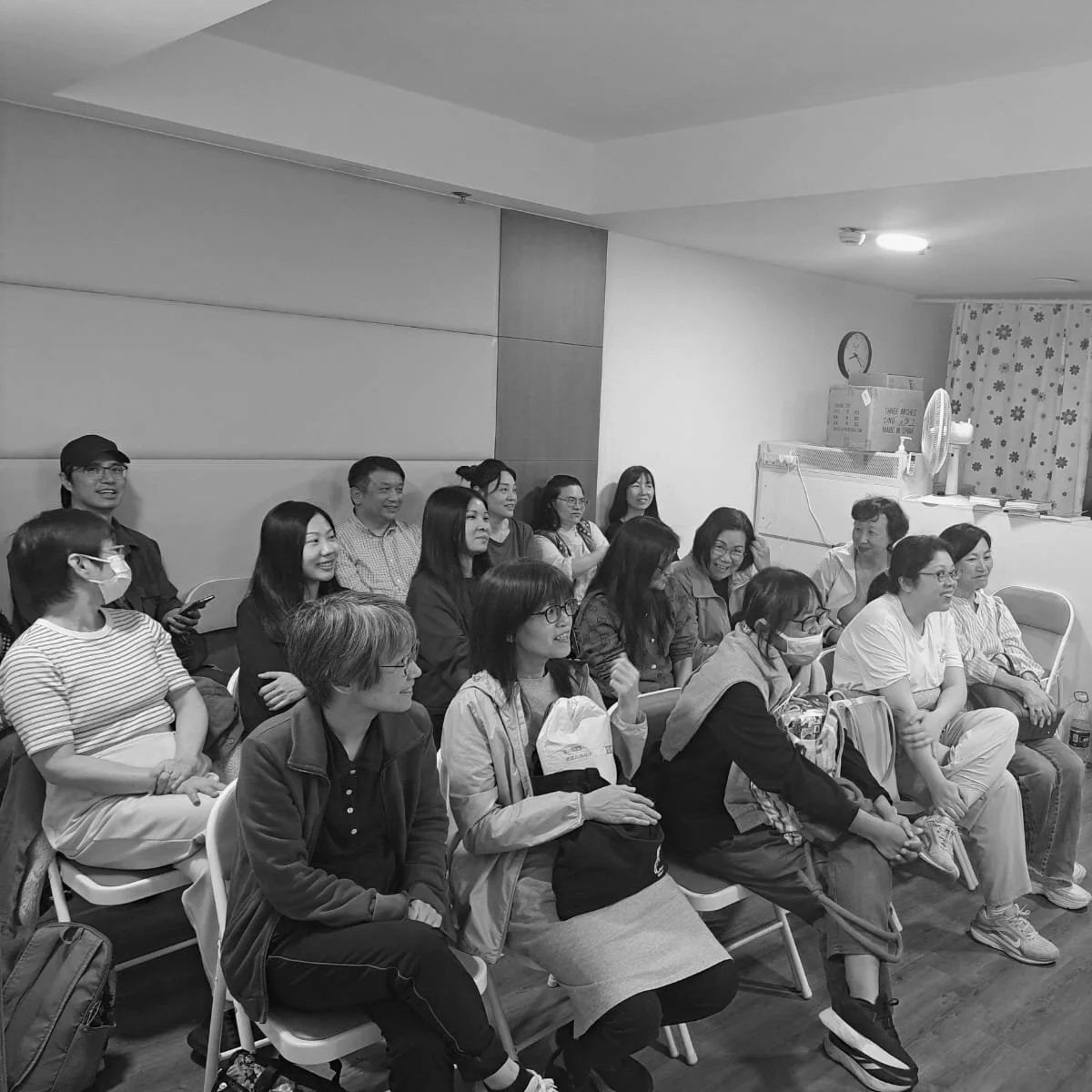 Group of people sitting and smiling during a presentation or event in a room.