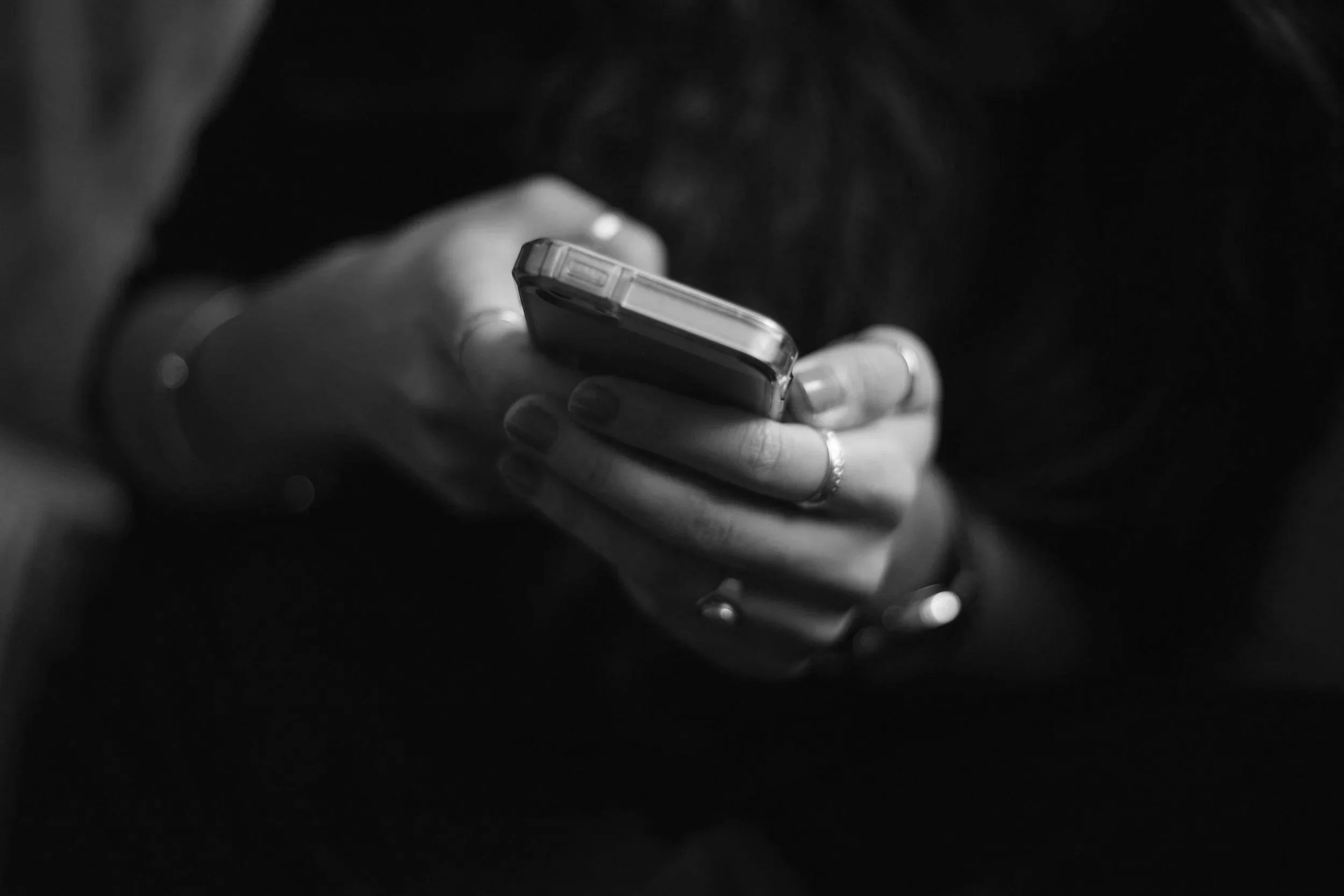 Close-up of a person's hand holding a smartphone in black and white.