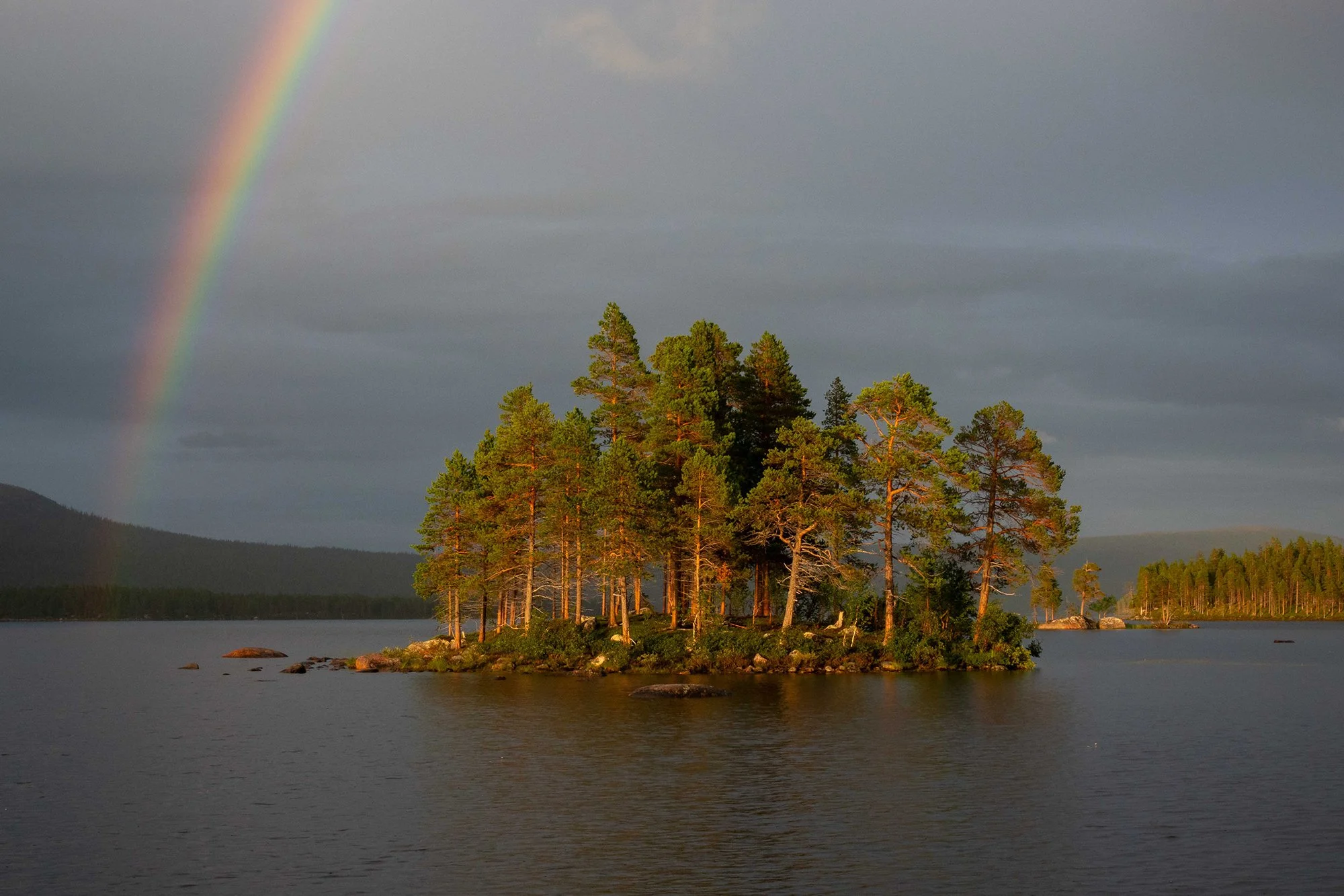 See mit einem Regenbogen am Himmel