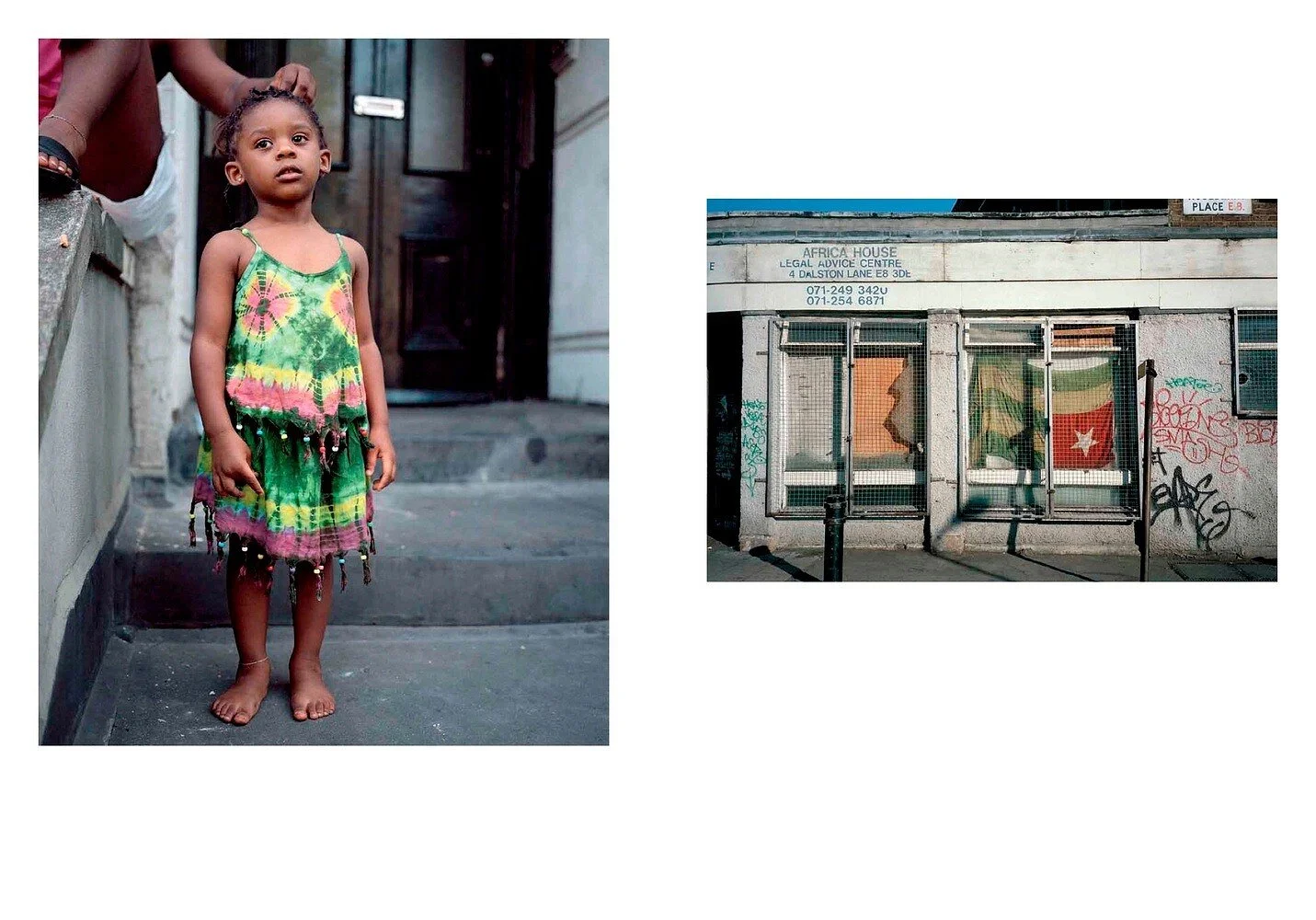 A young girl stands barefoot on a concrete staircase wearing colorful tie-dye clothing, looking at the camera. An adult is holding her hair. Next to her is a gray wall and a door. On the right, there is a building with a sign for Africa House Legal A