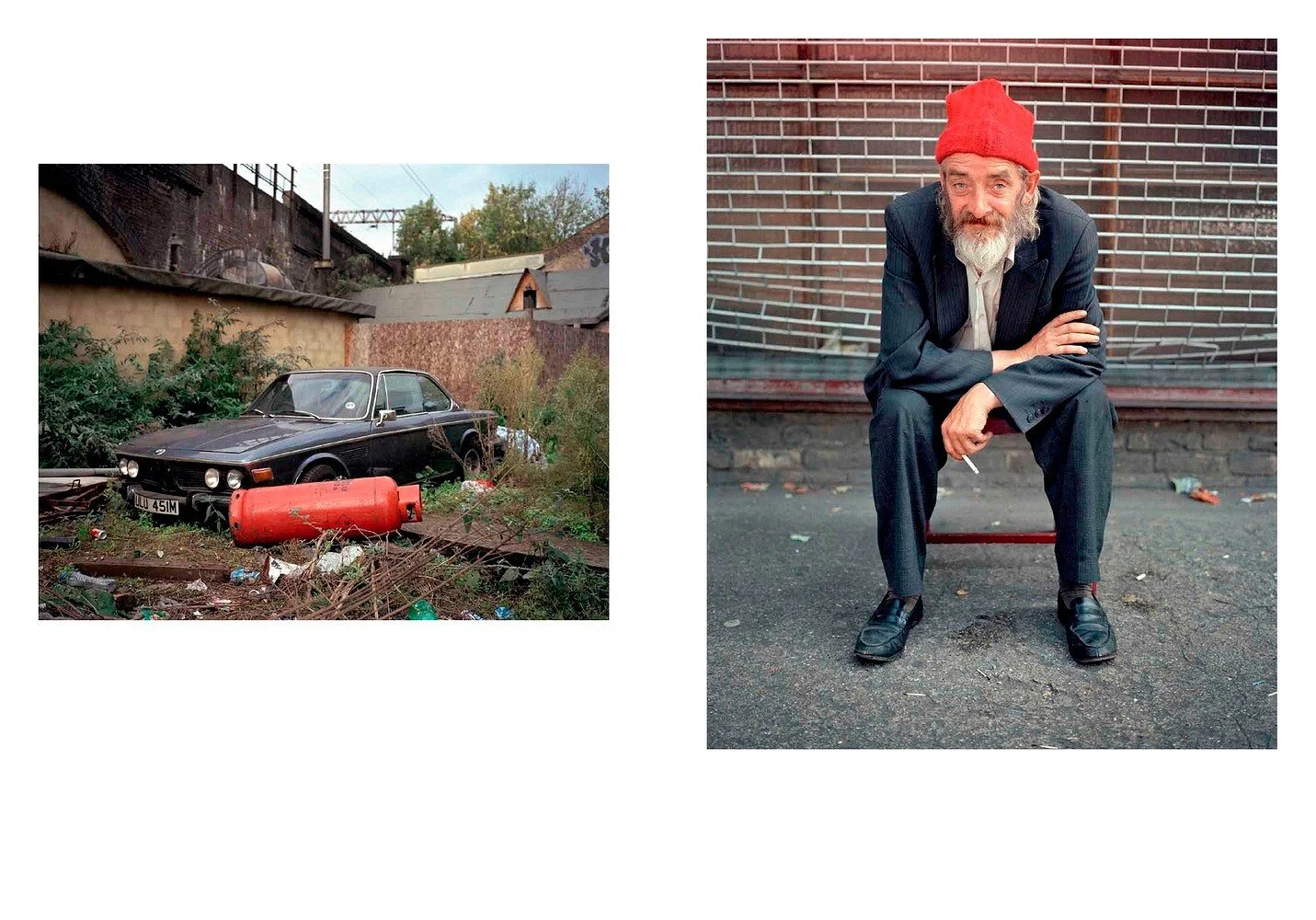 Side-by-side images: a vintage black car abandoned in a junkyard with overgrown weeds and debris, and a man with a beard wearing a red beanie, black suit, and dress shoes, sitting on a small red stool against a brick wall.