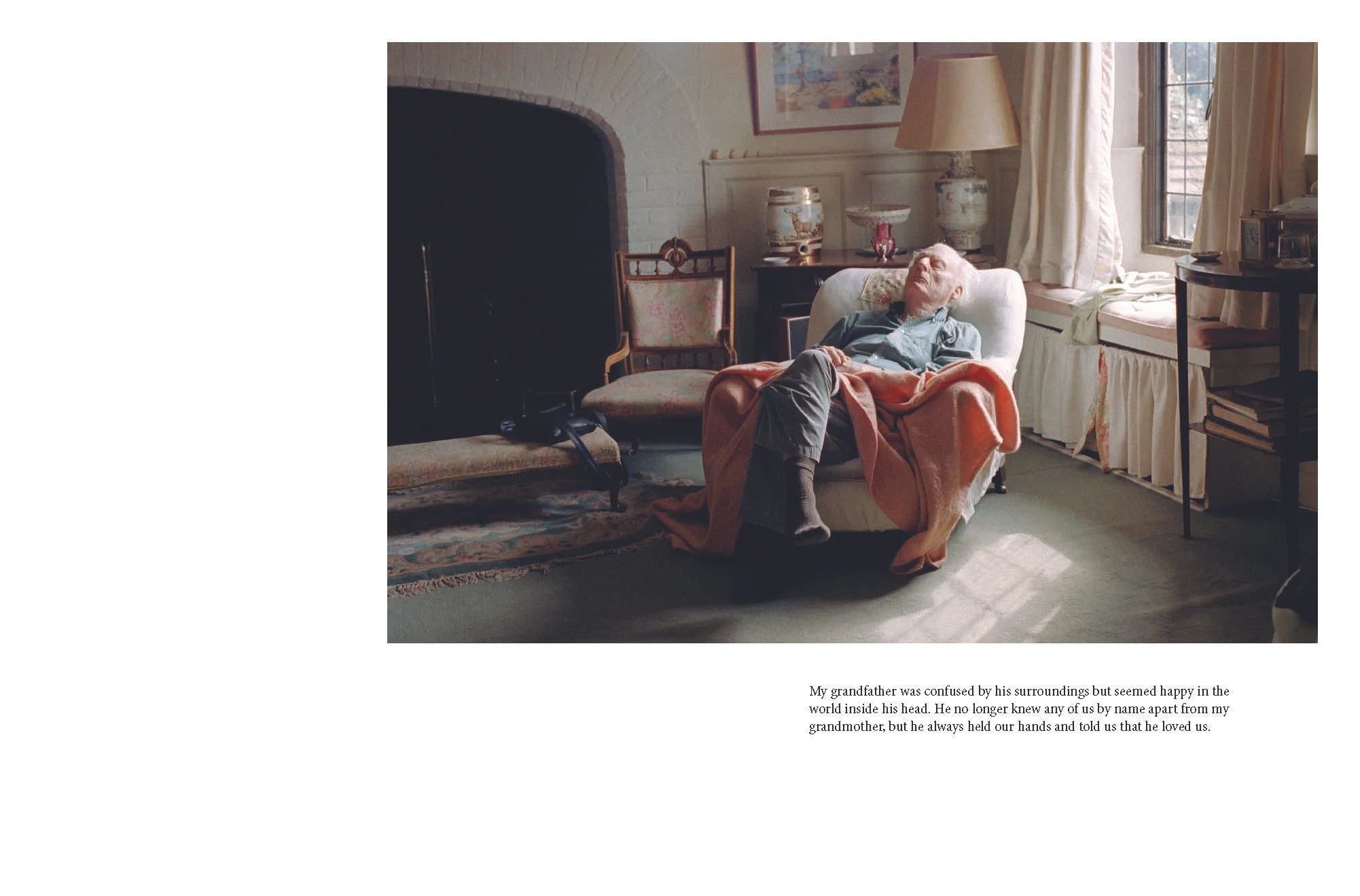 An elderly man with white hair and glasses is sleeping in a cozy living room, seated on an armchair with a blanket draped over him. The room has a large window with curtains, a fireplace, and various decorative items on tables. There is a caption bel