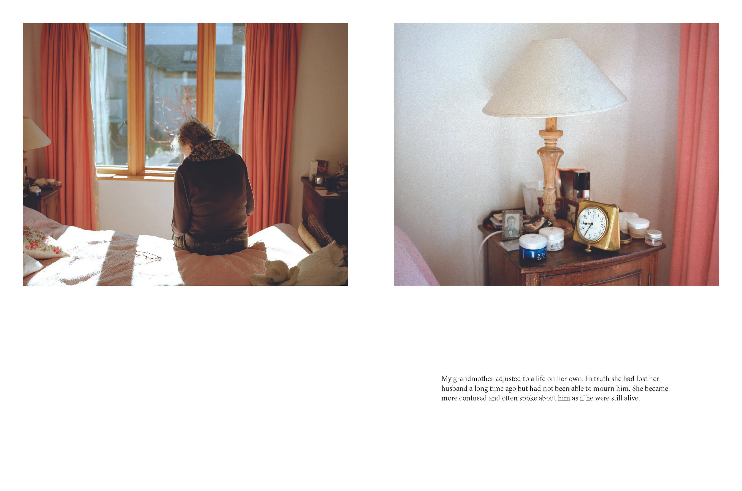 A woman sits on a bed in a bedroom with orange curtains, looking out the window. A wooden nightstand with a lamp, a clock, and personal items is next to the bed. A small teddy bear is on the bed.