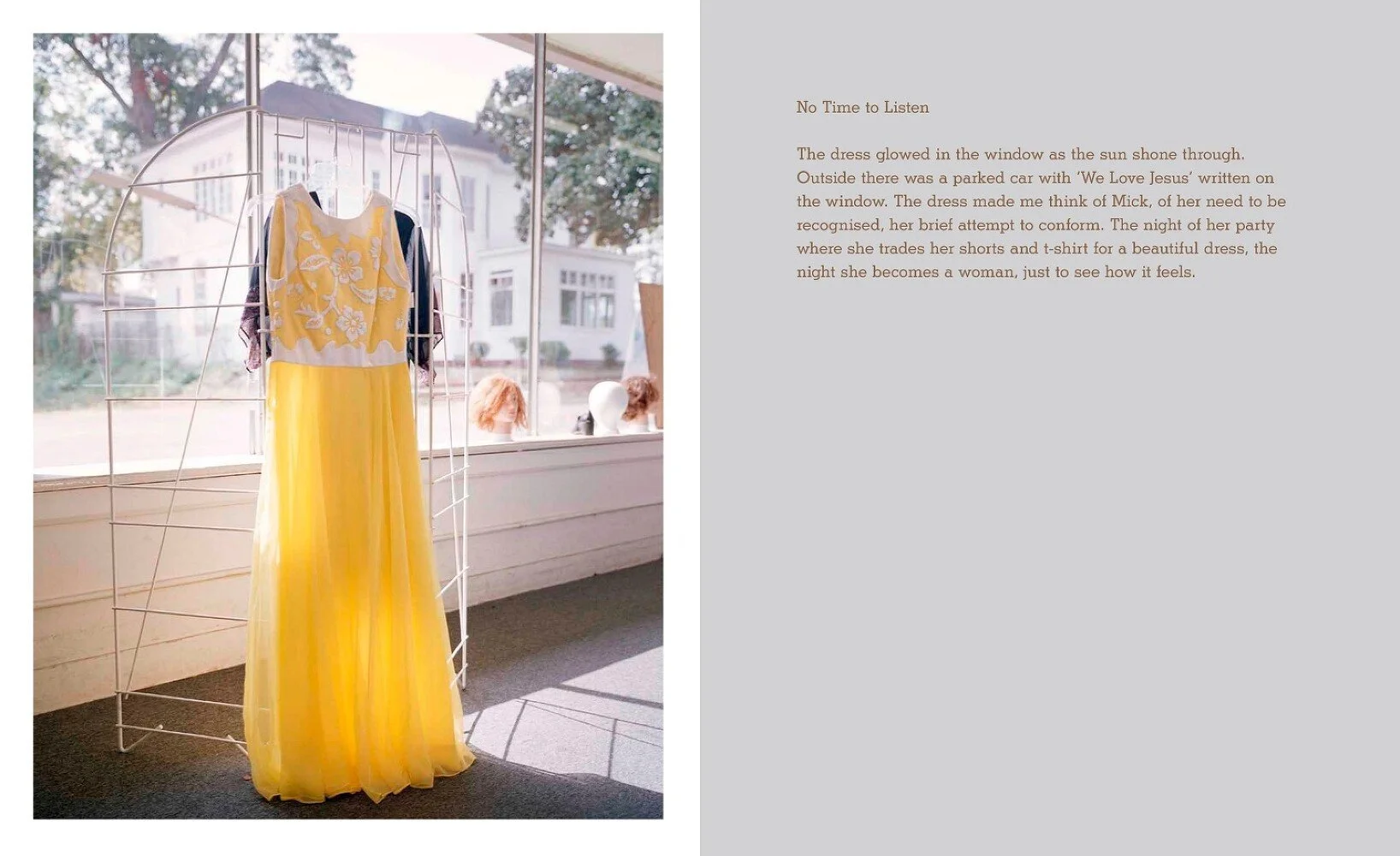 Yellow and white dress displayed on a clothing rack near a window with mannequins in the background.