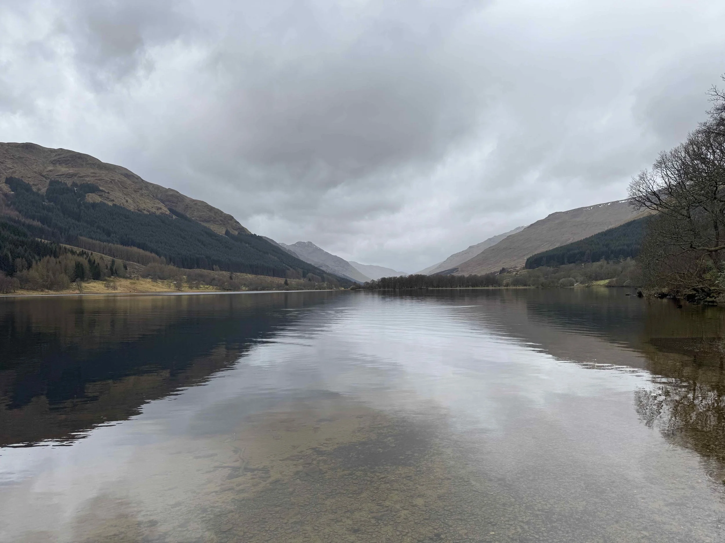 Calm loch landscape in Scotland with still water and mountains, reflecting a sense of space and uncertainty