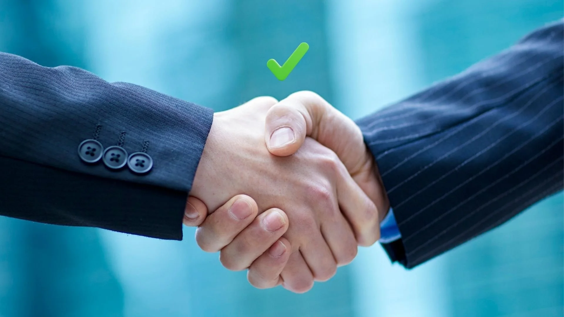 Close-up of two people shaking hands, one wearing a dark blue suit with stripe pattern, the other wearing a dark blue suit, with a green check mark above them.