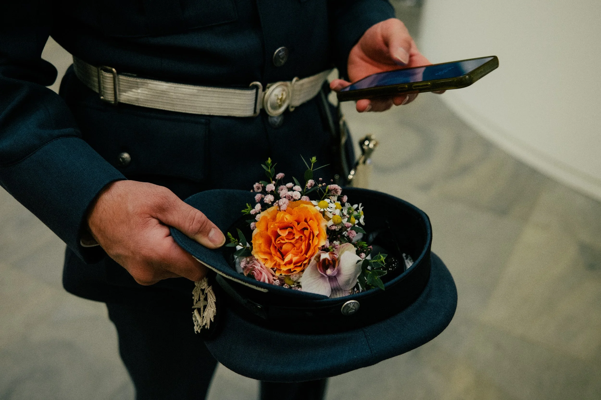 Nærbilde av en person som holder en blomsterbukett i en barnevogn og bruker en smarttelefon.