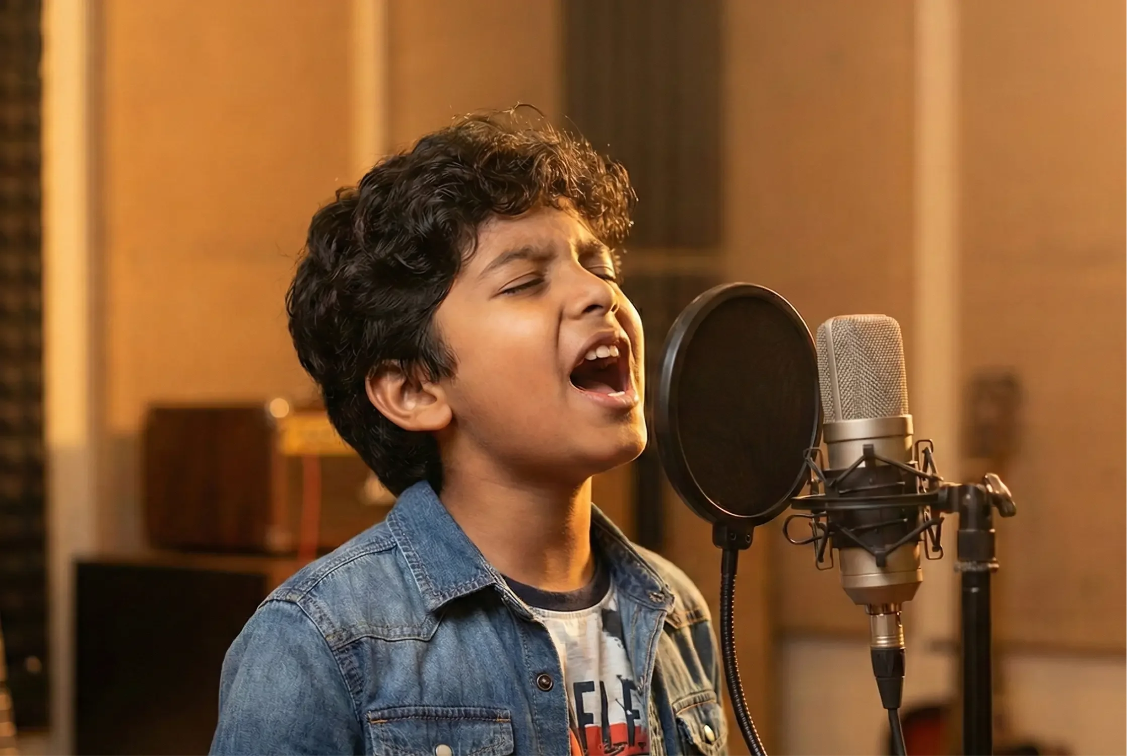 Young boy singing into a microphone in a recording studio.